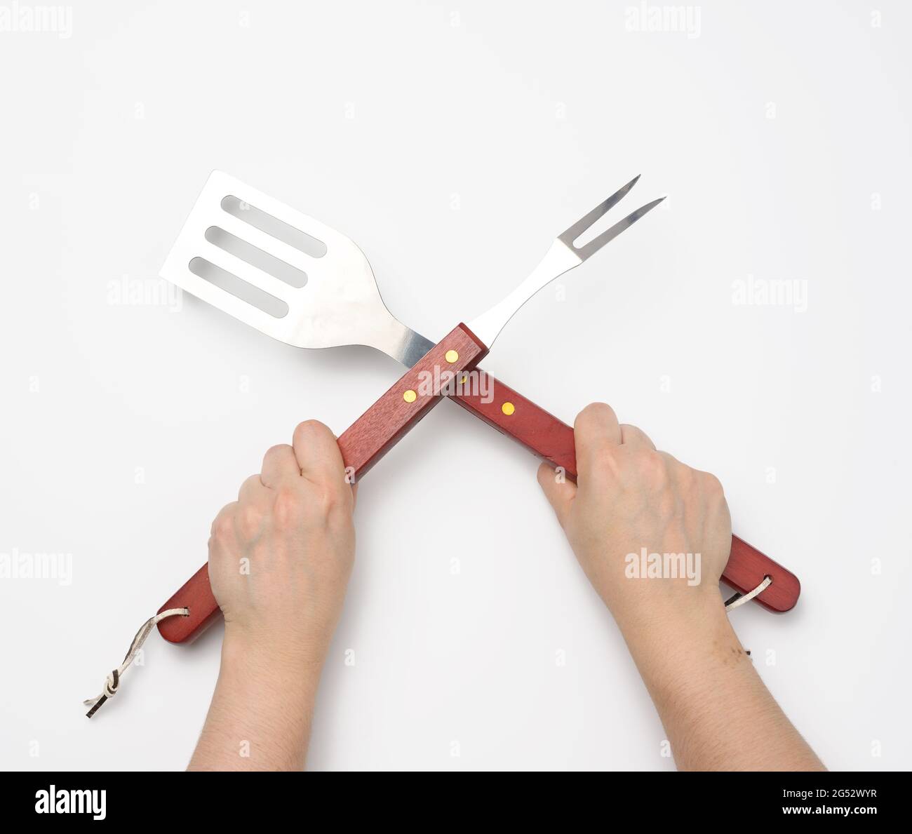 metal spatula and fork with a wooden handle for a picnic in a female hand  with painted red nails on a white background, utensils crossed Stock Photo  - Alamy
