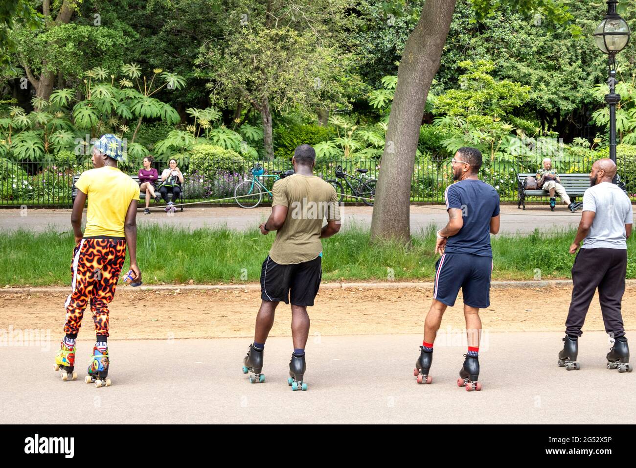 LONDON HYDE PARK LONDON'S CULTURAL DIVERSITY FOUR ROLLER SKATERS IN SERPENTINE ROAD DANCING TO MUSIC Stock Photo