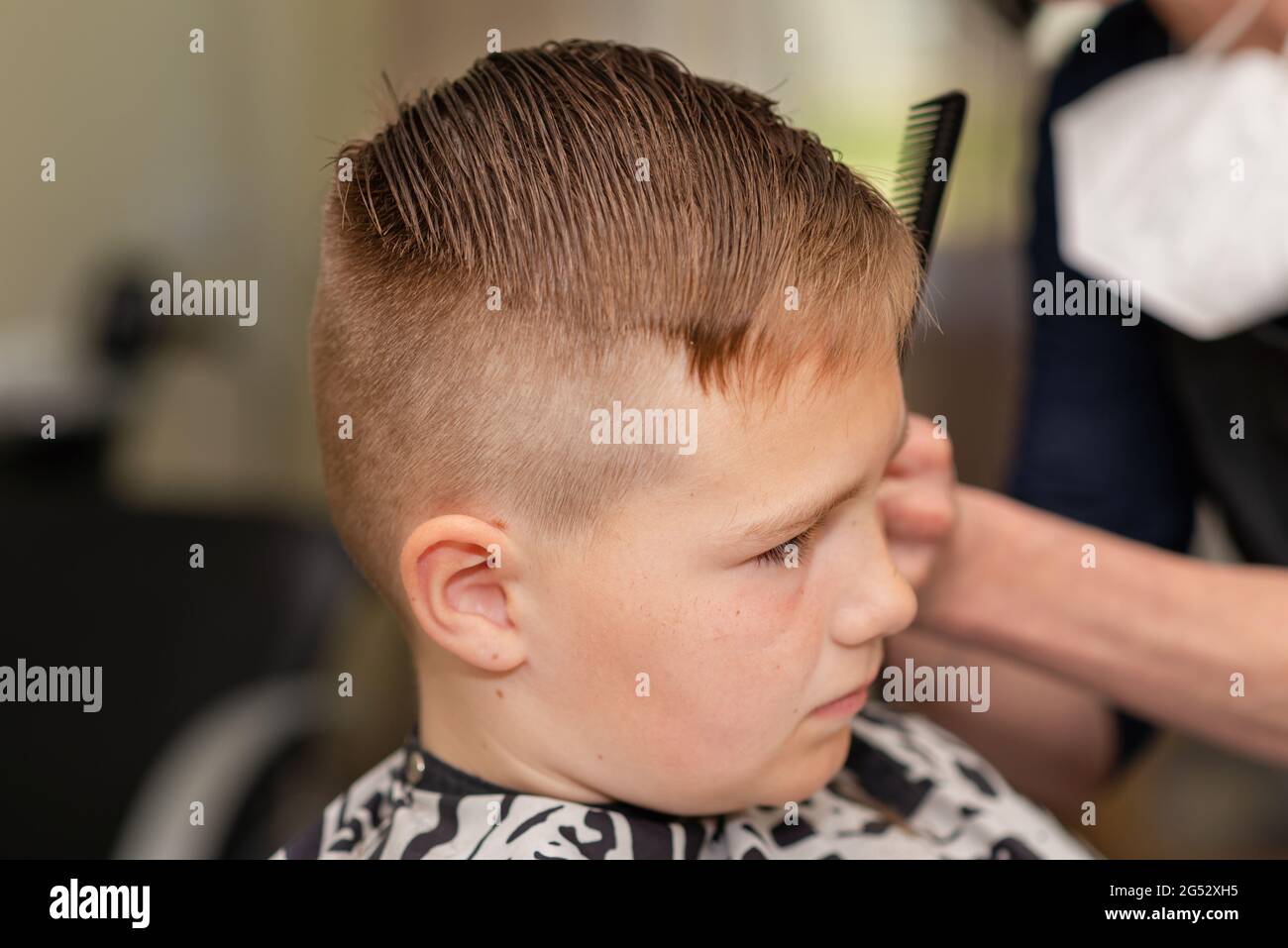 Cute kid boy have hair cut, professional barber doing haircut. Hairdress  for children. Kid side view portraits in the barbershop Stock Photo - Alamy