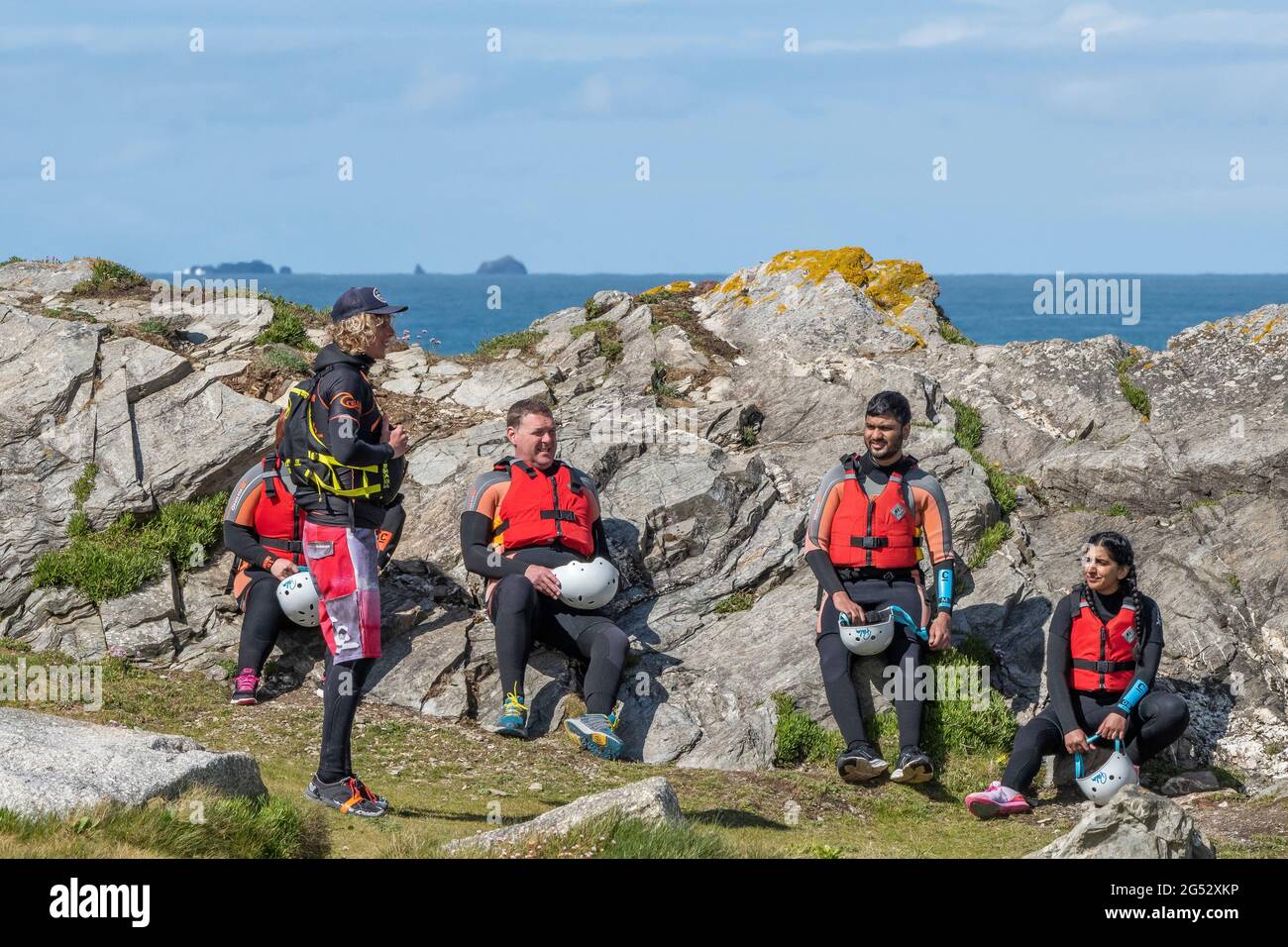 A group of holidaymakers listening to a safety talk given by a coasteering guide on Towan Head in Newquay in Cornwall. Stock Photo