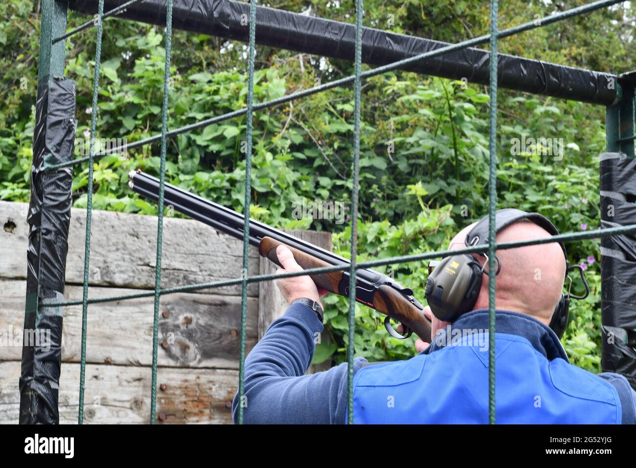 Main taking aim with his 12 gauge shot gun in a safety cage whilst clay pigeon shooting Stock Photo