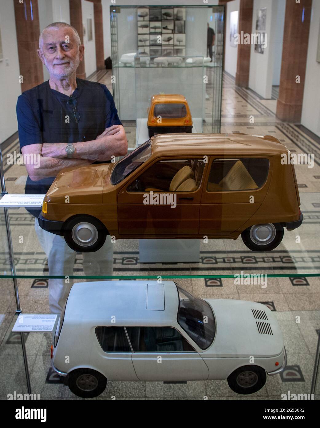 25 June 2021, Saxony, Chemnitz: In the Chemnitz Art Collections, the designer Karl Clauss Dietel stands behind a display case with models for the Trabant P601 N passenger car (station wagon), 1979/80 (above) and the Wartburg 353 Coupé passenger car, 1965/66, which he designed together with the designer Lutz Rudolph. Entitled 'Simson, Diamant, Erika - Form Design by Karl Clauss Dietel', the show provides an insight into the designer's oeuvre. Aware of the importance of a cohesive oeuvre, Dietel archived his life's work for decades and in 2019 handed it over in its entirety to the care of the St Stock Photo