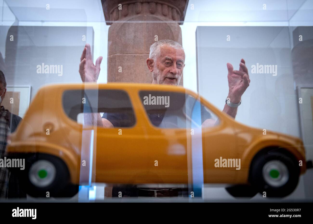 Chemnitz, Germany. 25th June, 2021. In the Chemnitz Art Collections, the designer Karl Clauss Dietel stands behind a display case with a vehicle model from 1971/72, which he designed together with the designer Lutz Rudolph. Entitled 'Simson, Diamant, Erika - Form Design by Karl Clauss Dietel', the show provides an insight into the designer's work. Aware of the importance of a cohesive oeuvre, Dietel archived his life's work for decades and in 2019 handed it over in its entirety to the care of the Städtische Kunstsammlungen. Credit: Hendrik Schmidt/dpa-Zentralbild/dpa/Alamy Live News Stock Photo