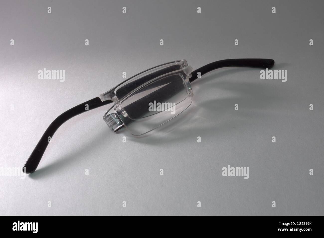 folded reading glasses, broken in half along the bridge between lenses ...