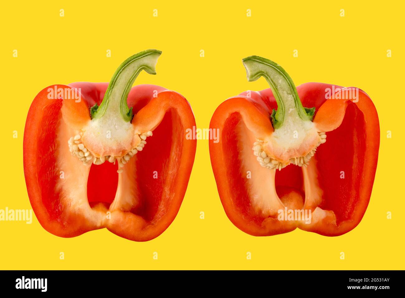 Red bell pepper cut in half in cross section, isolated on yellow Stock Photo