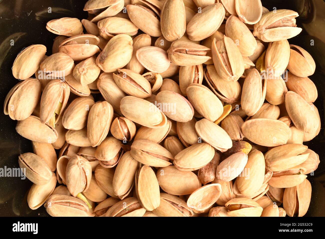 Organic salted delicious pistachios in a black plate, close-up,  top view. Stock Photo