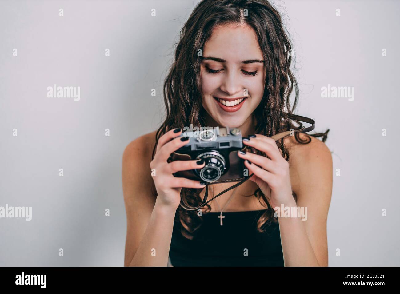 Beautiful teen girl holding an old, retro film camera. Isolated, white, gray background Stock Photo