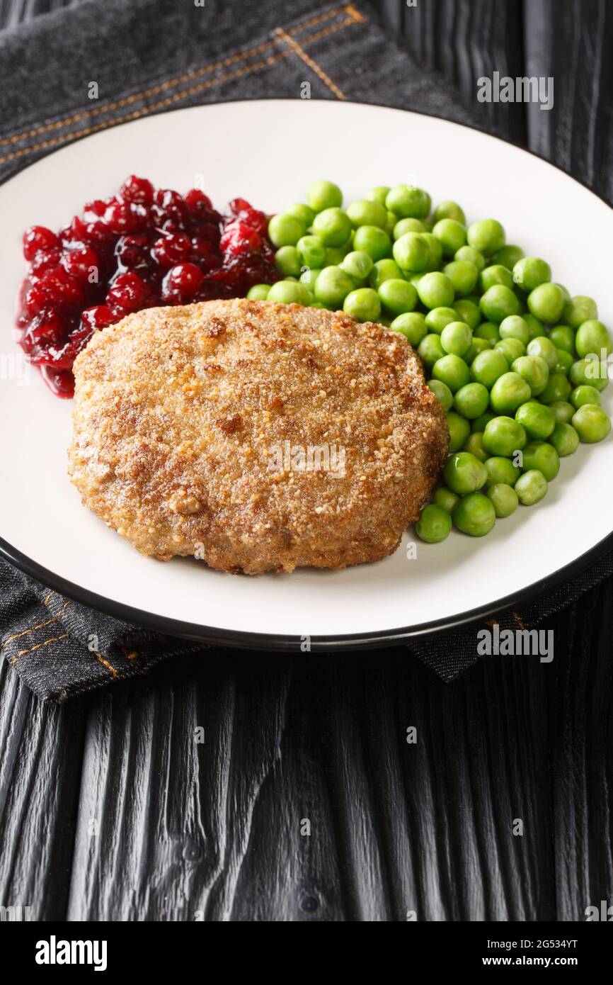 Swedish food Veal burgers Wallenbergare with green peas closeup in the plate on the table. Vertical Stock Photo
