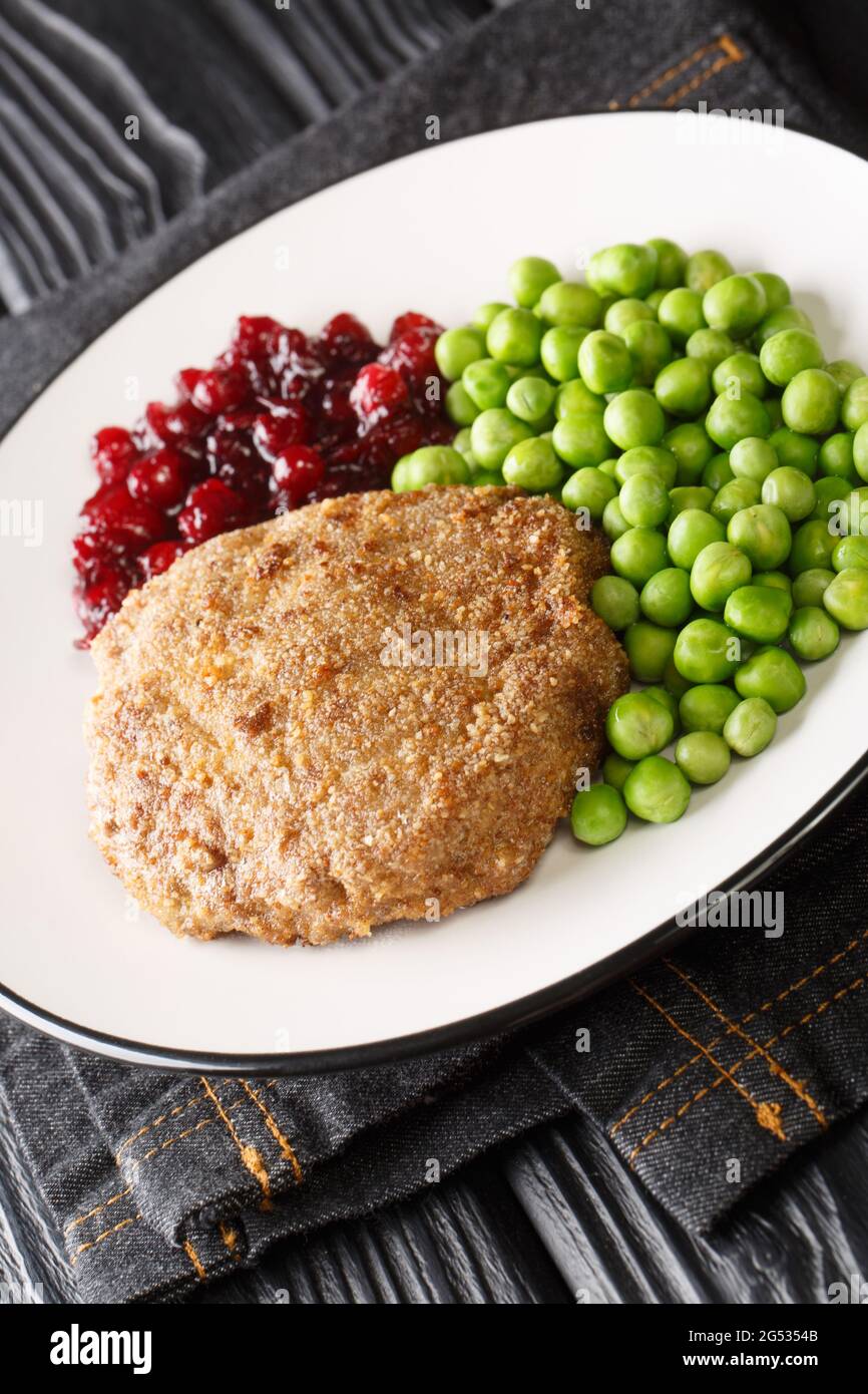 Veal burger with green peas and lingonberry jam close-up in a plate on the table. Vertical Stock Photo
