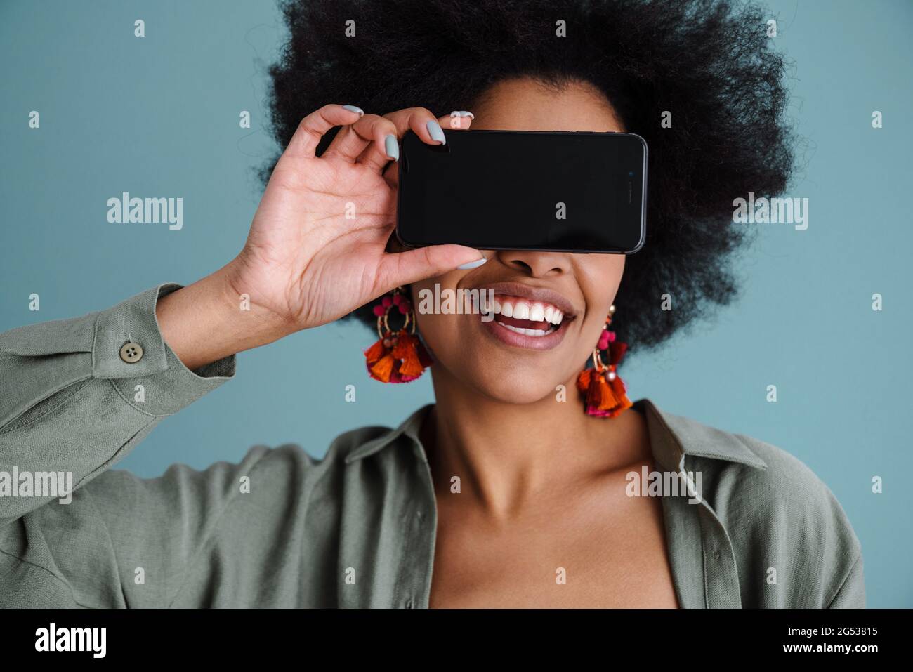 Joyful african american girl making fun with mobile phone isolated over blue background Stock Photo