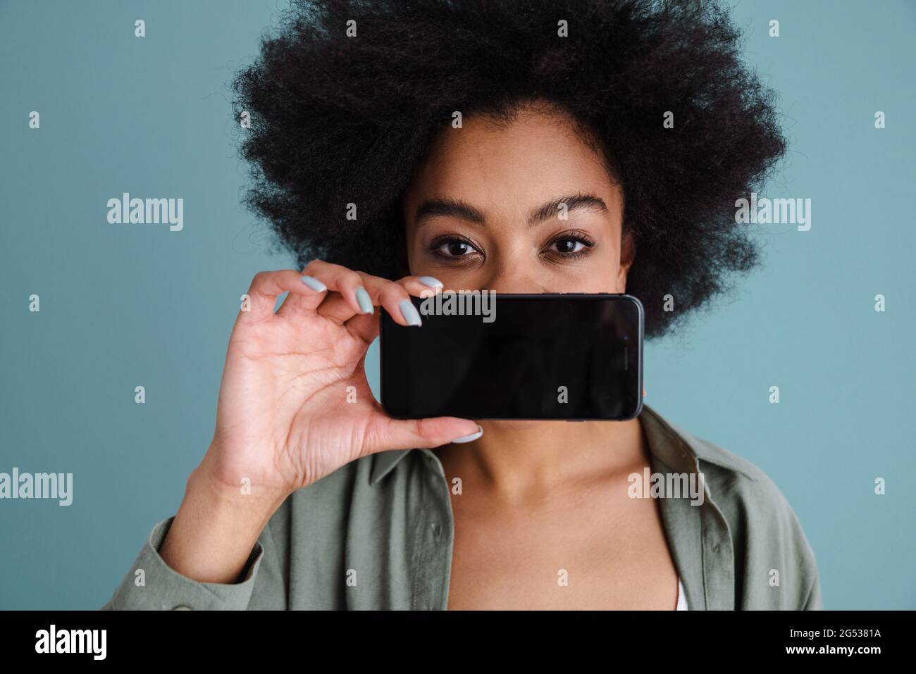 Joyful african american girl taking photo on mobile phone isolated over blue background Stock Photo