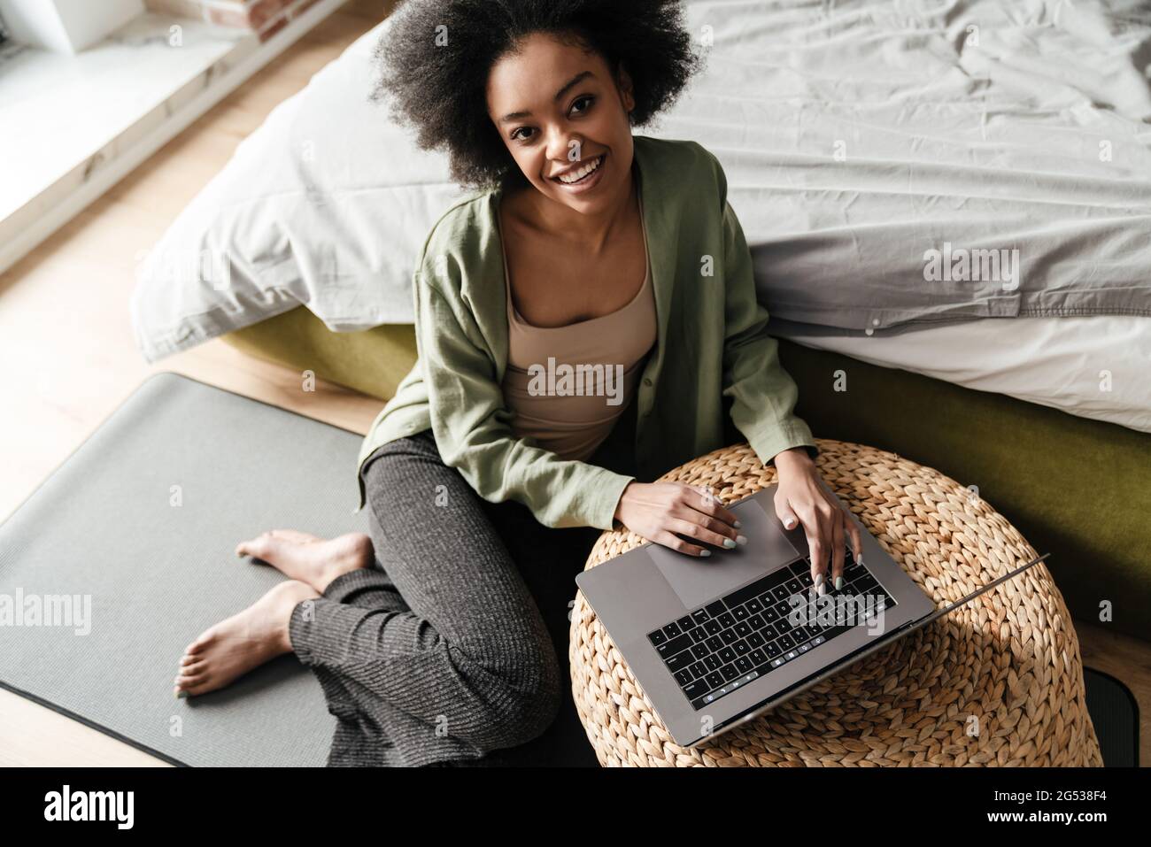 Happy african american girl using laptop while sitting on floor at home ...