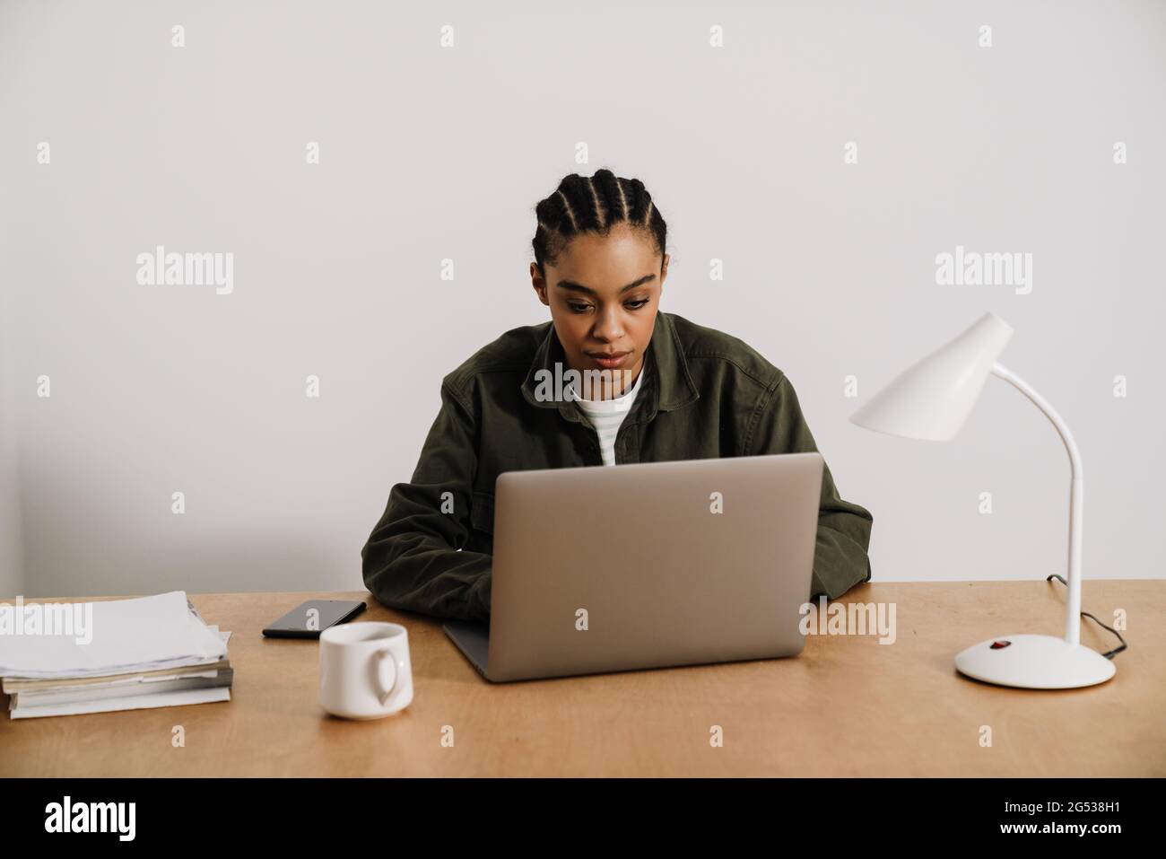 Black young woman working with laptop while sitting at table in office ...