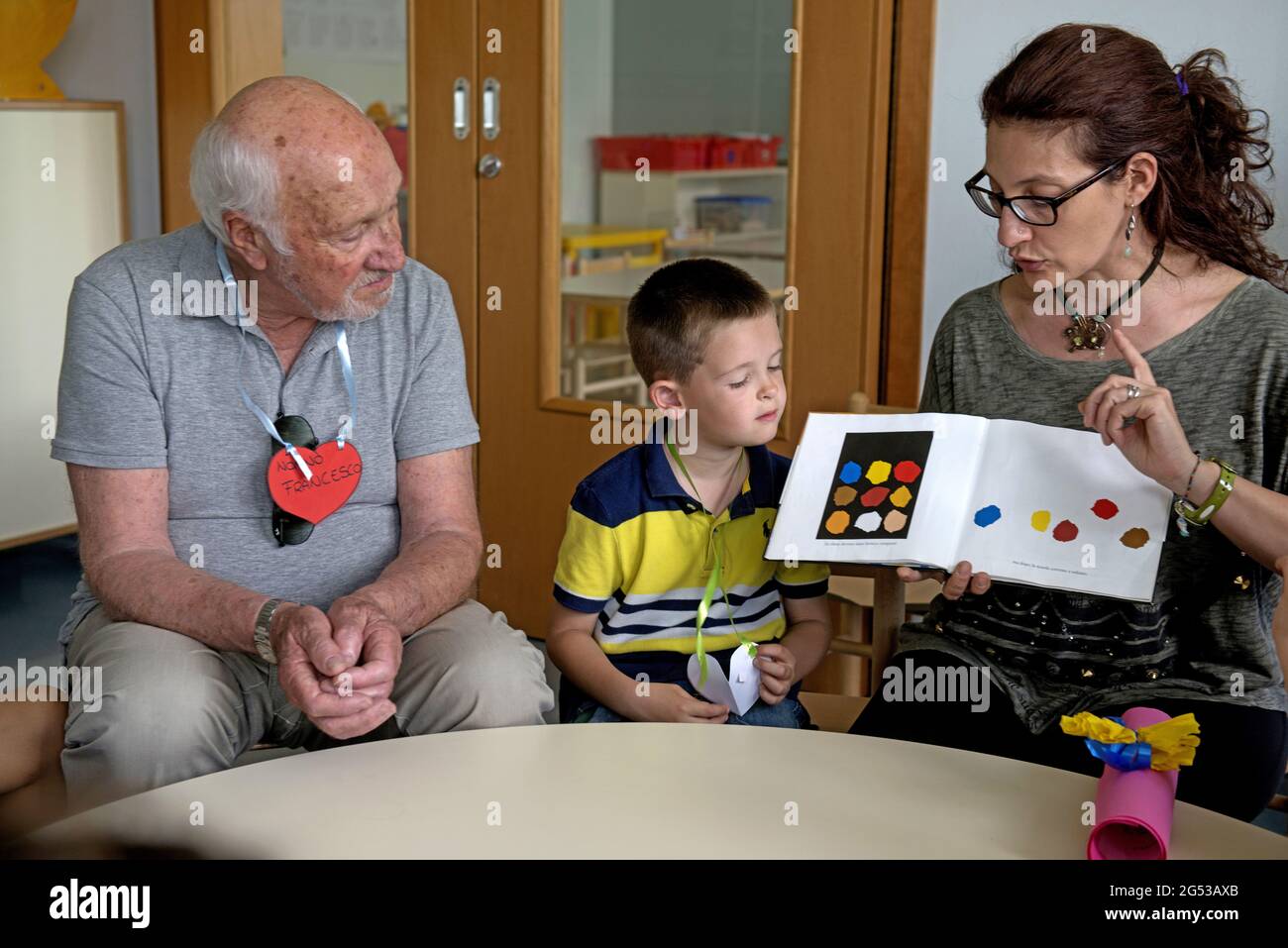 Grandparents teaching, playing and leraning with children of a kindergarten inside Civitas Vitae, a residence for elderly, in Padua, Italy Stock Photo