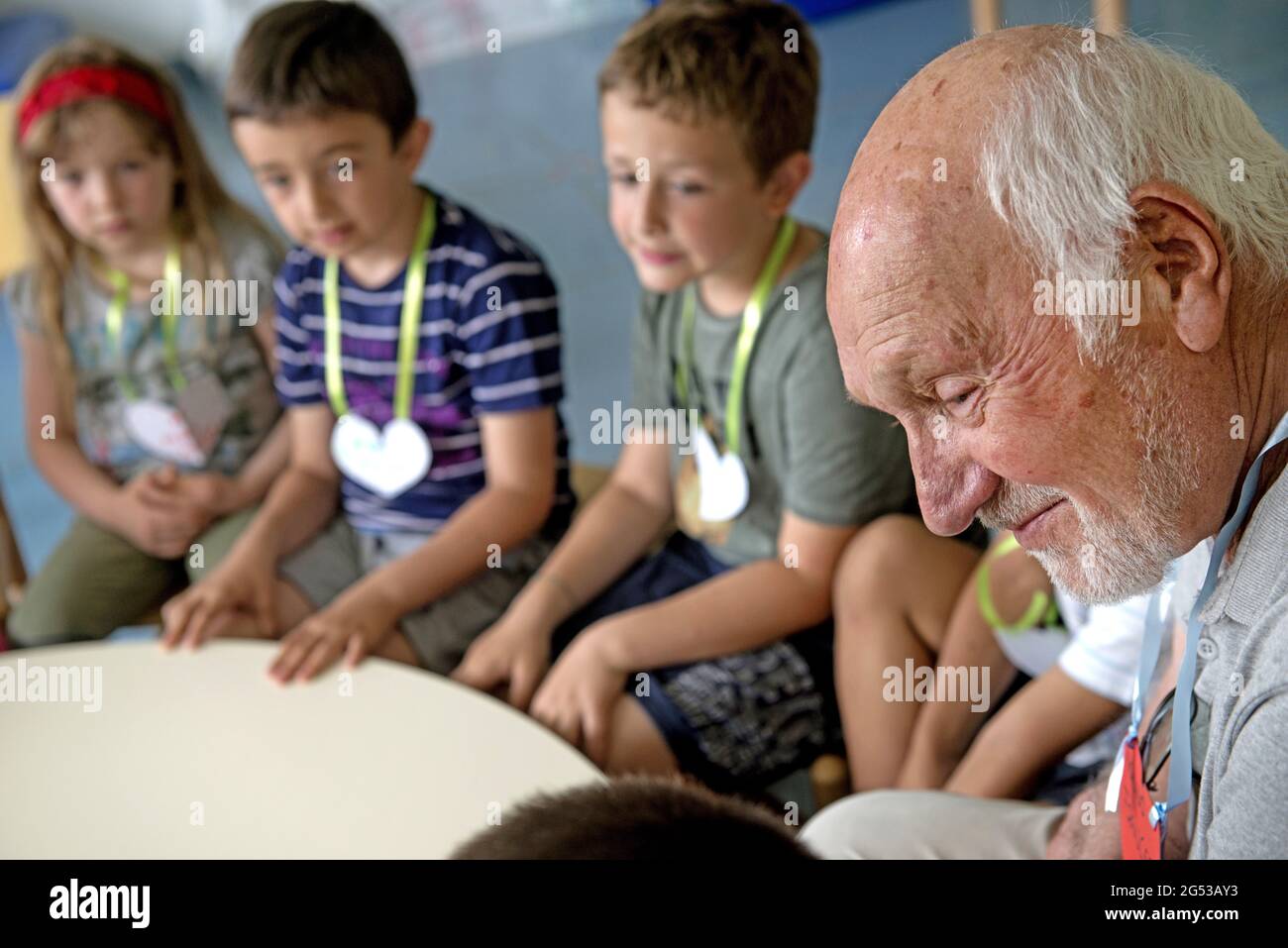 Grandparents teaching, playing and leraning with children of a kindergarten inside Civitas Vitae, a residence for elderly, in Padua, Italy Stock Photo