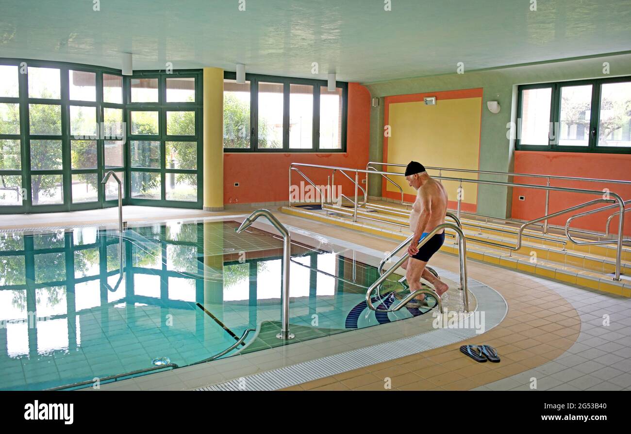 Elderly man enters in a swimming pool, at Civitas Vitae, a residence for elderly, in Padua, Italy Stock Photo