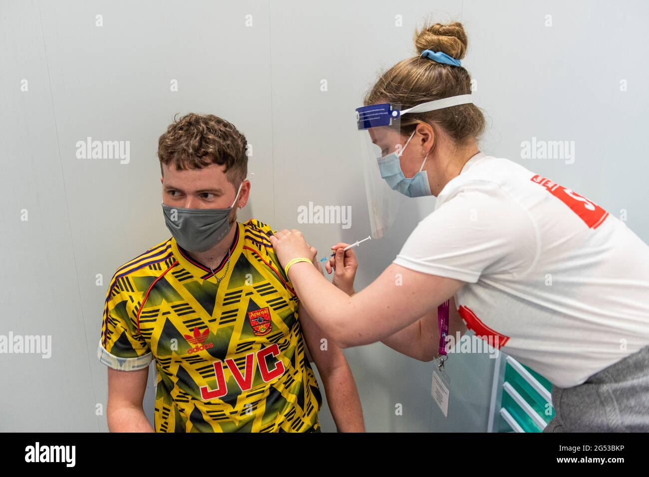 London, UK. 25th June, 2021. Gunners fan Jake McDaid, aged 26, receives a first dose of the Pfizer vaccine at a pop-up mass vaccination clinic Arsenal's Emirates Stadium as part of a “Gunner Get Jabbed” event organised by Islington Council, the local GP federation and the football club. The NHS is also promoting a number of walk-in clinics this weekend across the capital to try to increase the number of over 18s receiving a jab as cases of the Delta variant are reported to be on the rise. Credit: Stephen Chung/Alamy Live News Stock Photo