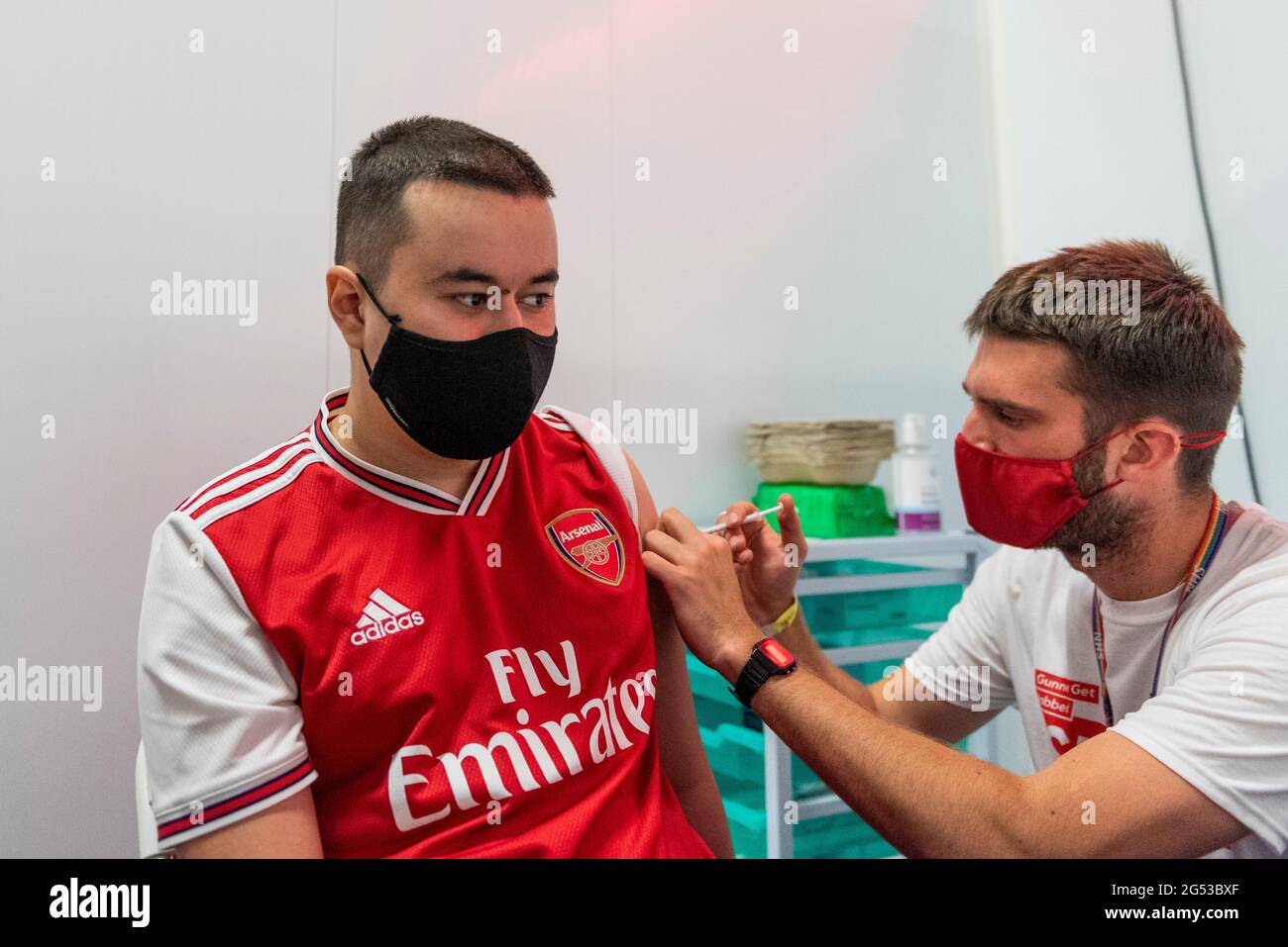 London, UK. 25th June, 2021. Gunners fan Lorenzo Homa, aged 22, receives a first dose of the Pfizer vaccine at a pop-up mass vaccination clinic Arsenal's Emirates Stadium as part of a “Gunner Get Jabbed” event organised by Islington Council, the local GP federation and the football club. The NHS is also promoting a number of walk-in clinics this weekend across the capital to try to increase the number of over 18s receiving a jab as cases of the Delta variant are reported to be on the rise. Credit: Stephen Chung/Alamy Live News Stock Photo