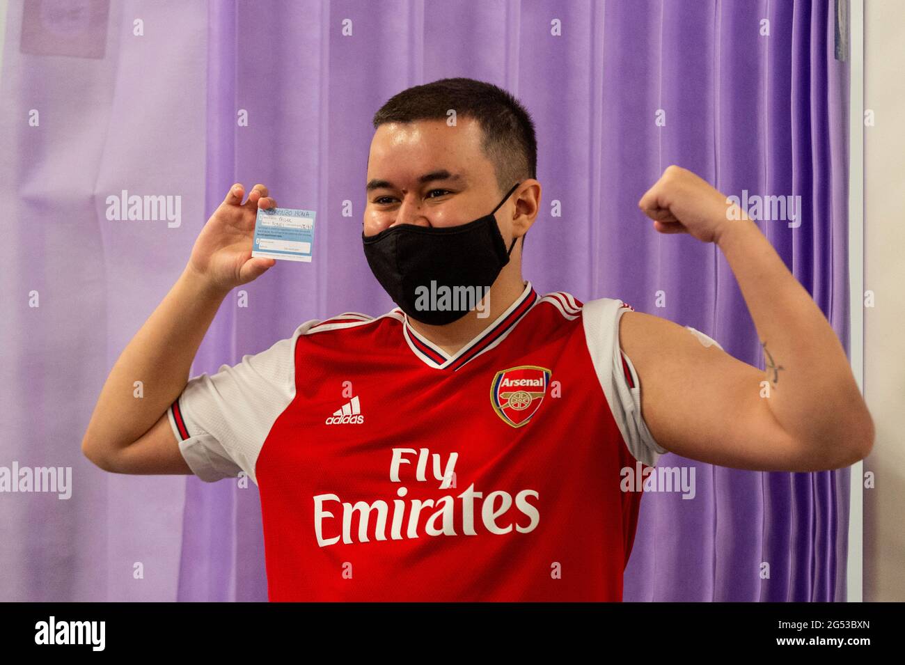 London, UK. 25th June, 2021. Gunners fan Lorenzo Homa, aged 22, poses after receiving a first dose of the Pfizer vaccine at a pop-up mass vaccination clinic Arsenal's Emirates Stadium as part of a “Gunner Get Jabbed” event organised by Islington Council, the local GP federation and the football club. The NHS is also promoting a number of walk-in clinics this weekend across the capital to try to increase the number of over 18s receiving a jab as cases of the Delta variant are reported to be on the rise. Credit: Stephen Chung/Alamy Live News Stock Photo