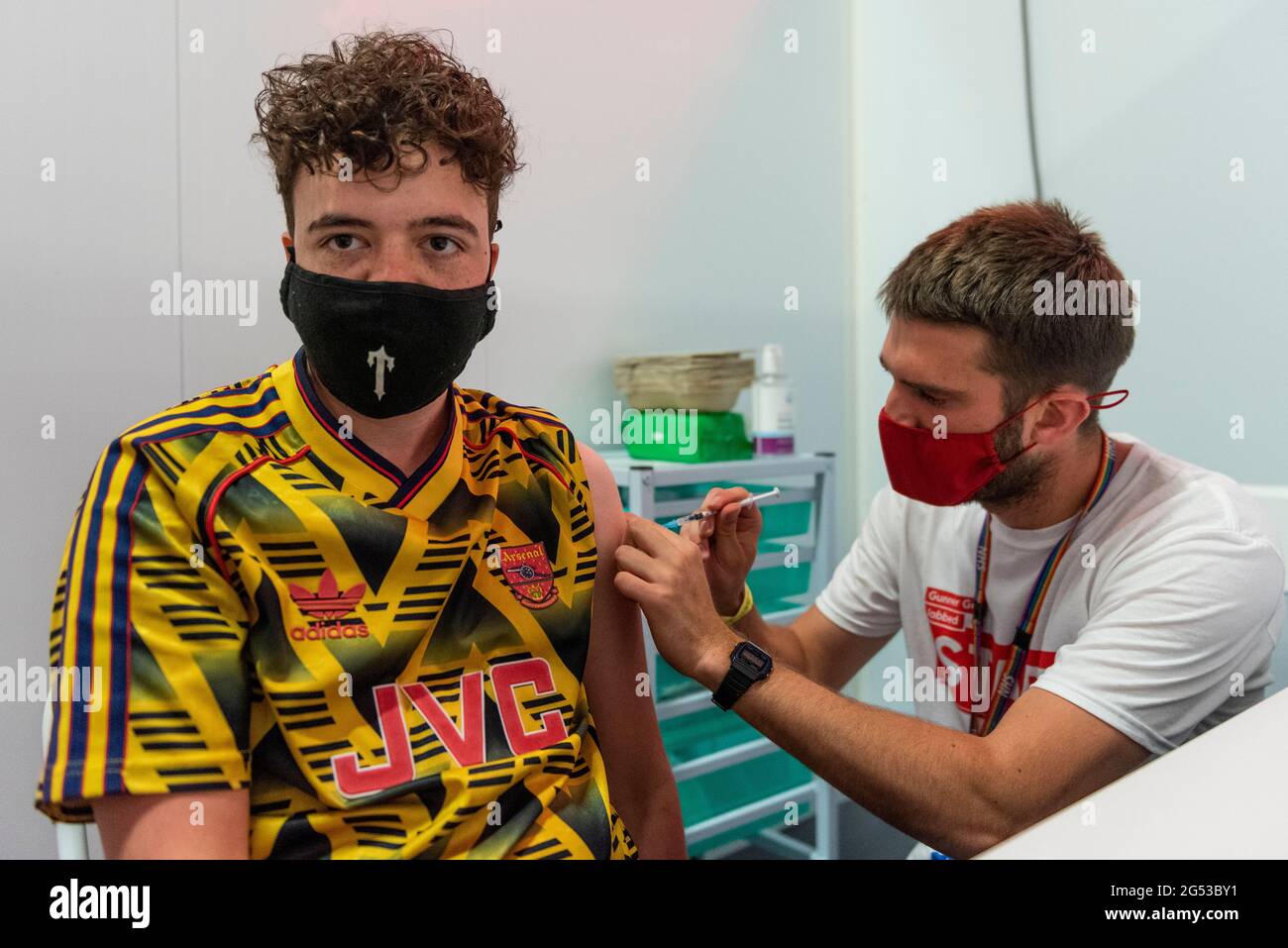 London, UK. 25th June, 2021. Gunners fan Sam Dobbie, aged 26, receives a first dose of the Pfizer vaccine at a pop-up mass vaccination clinic Arsenal's Emirates Stadium as part of a “Gunner Get Jabbed” event organised by Islington Council, the local GP federation and the football club. The NHS is also promoting a number of walk-in clinics this weekend across the capital to try to increase the number of over 18s receiving a jab as cases of the Delta variant are reported to be on the rise. Credit: Stephen Chung/Alamy Live News Stock Photo