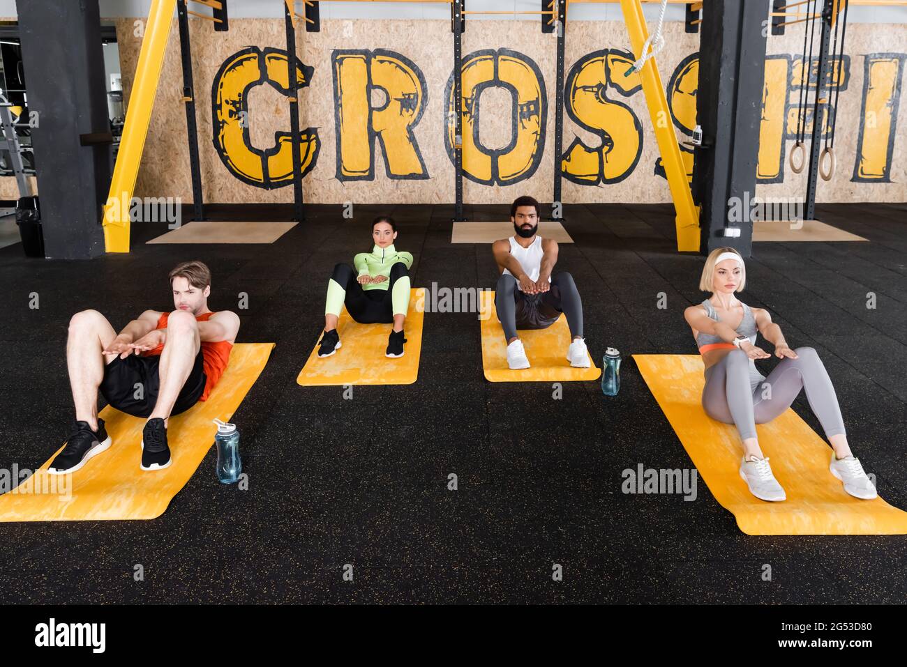 young multiethnic people doing abs exercise on fitness mats Stock Photo