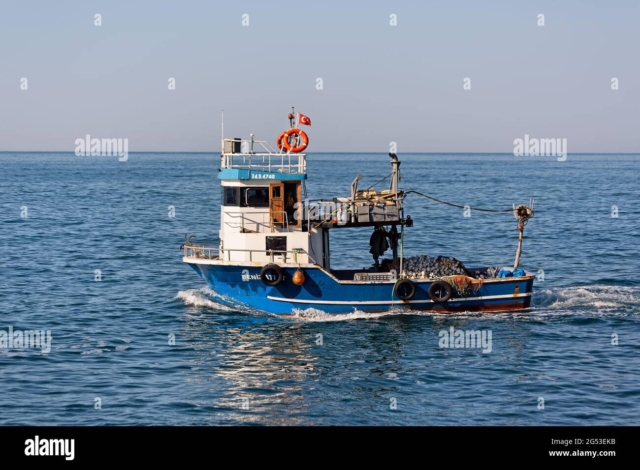 Small fishing boat carrying nets sailing through Karadeniz from Marmara Sea. Side view. Rumelifeneri, Istanbul / Turkey. Stock Photo