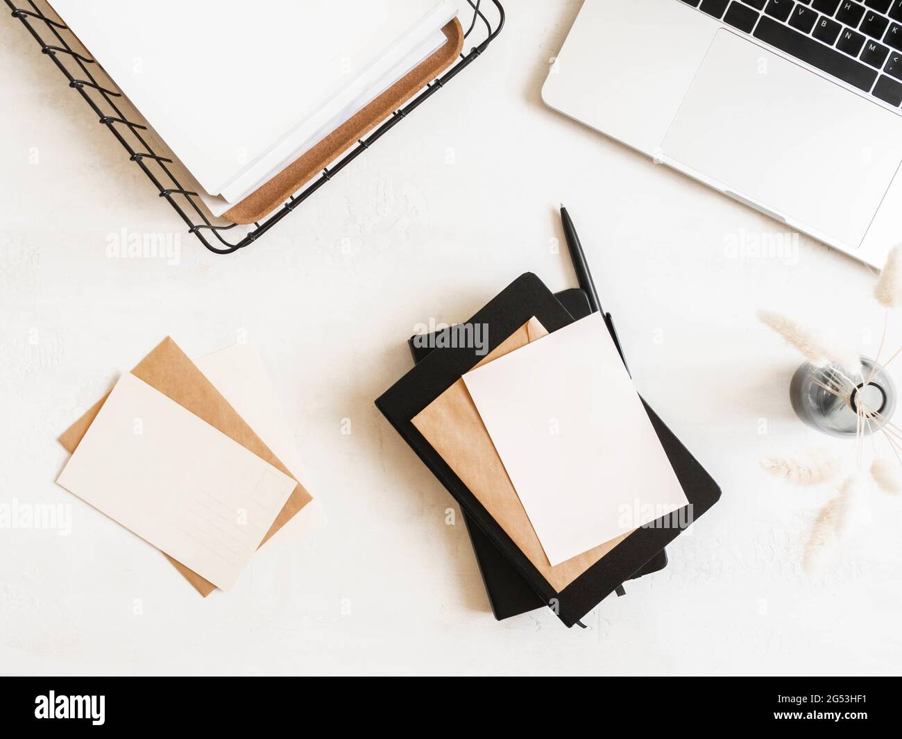 Home office desk with laptop, notebook, storage basket, dry flowers in