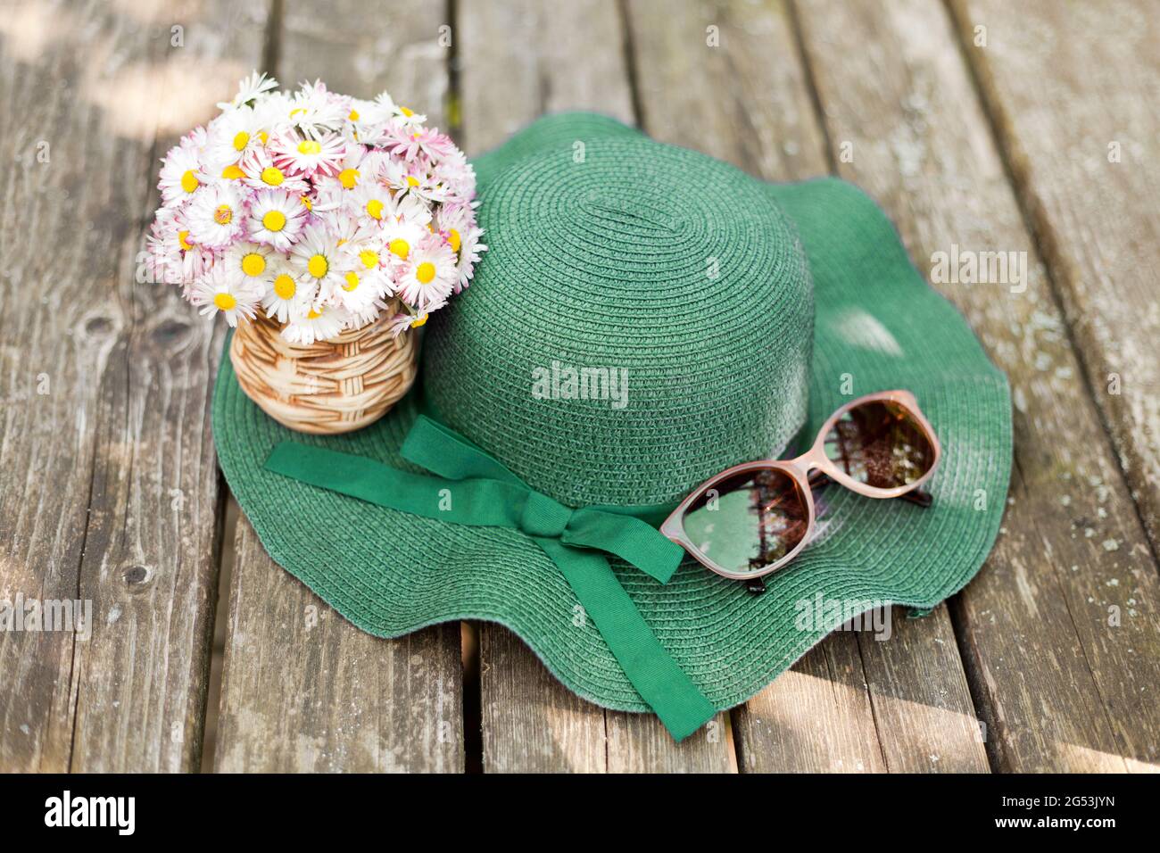daisies lying on a green hat near sunglasses. Designer old-fashioned floristics bouquet of meadow and wild flowers. A romantic photo of a cute spring Stock Photo