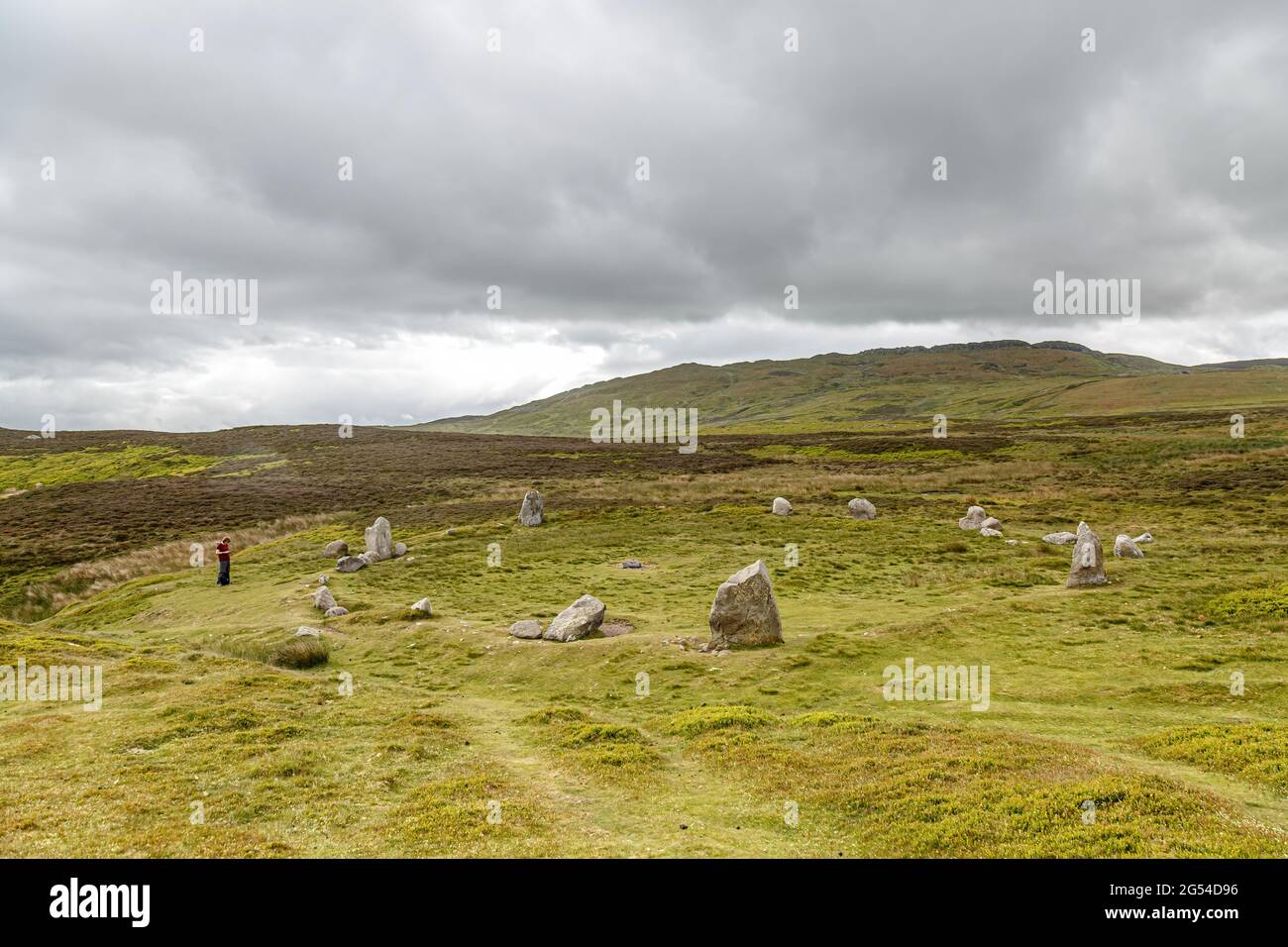 A single female using her phone at the Neolithic Site commonly referred to a Druid Circle near Penmaenmawr, Gwynedd, Wales Stock Photo