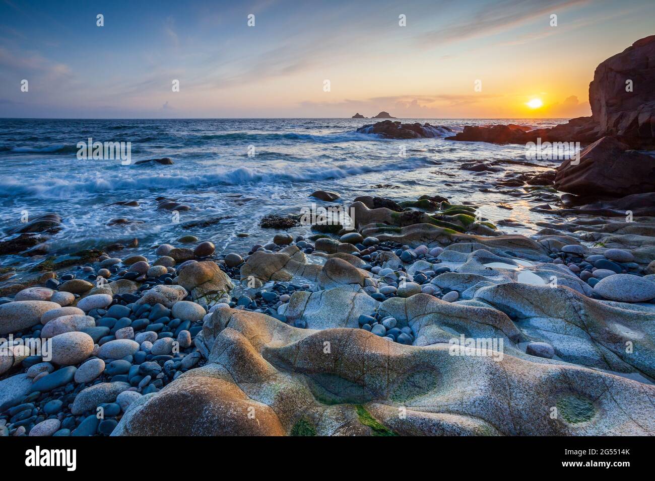 Sunset at Porth Nanven in Cornwall, with the Brison Rocks in the distance. Stock Photo
