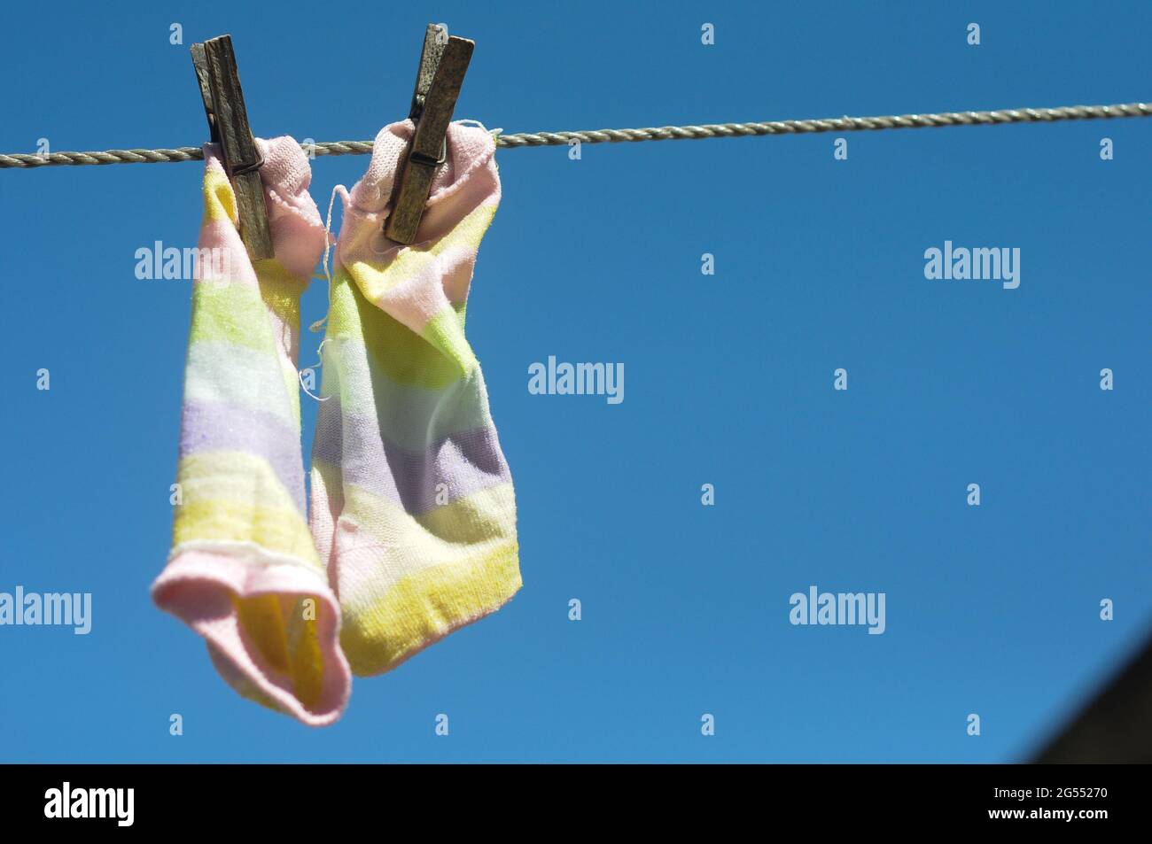 A pair of colorful short stockings hanging on a clothes line, with a blue sky in the background Stock Photo