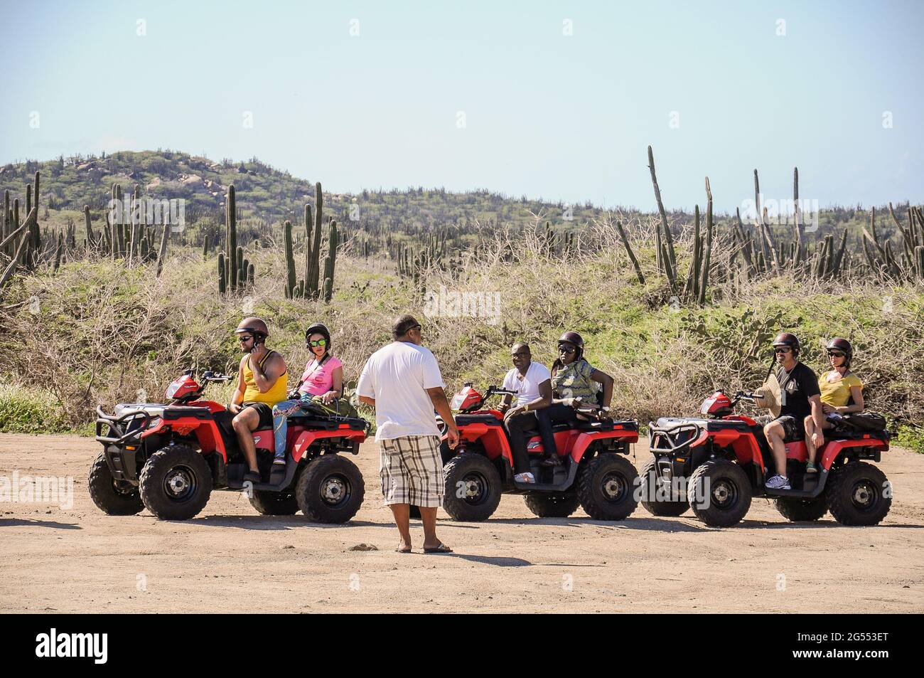 Group of people having a guided tour by some quads with some cacti in the background in Aruba Stock Photo