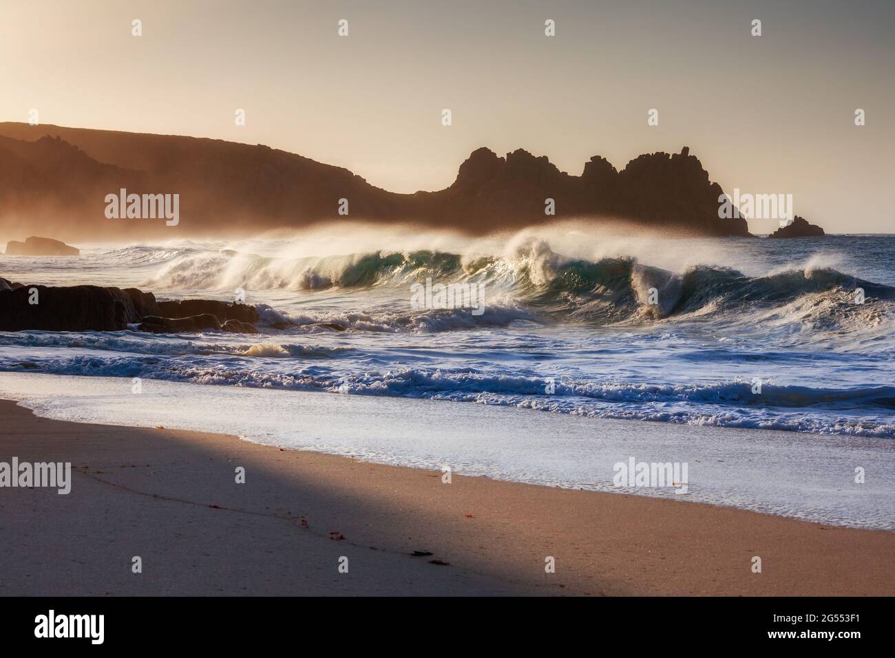 A wave crashing onto Pednvounder Beach near Porthcurno in Cornwall on a bright summer morning. Stock Photo