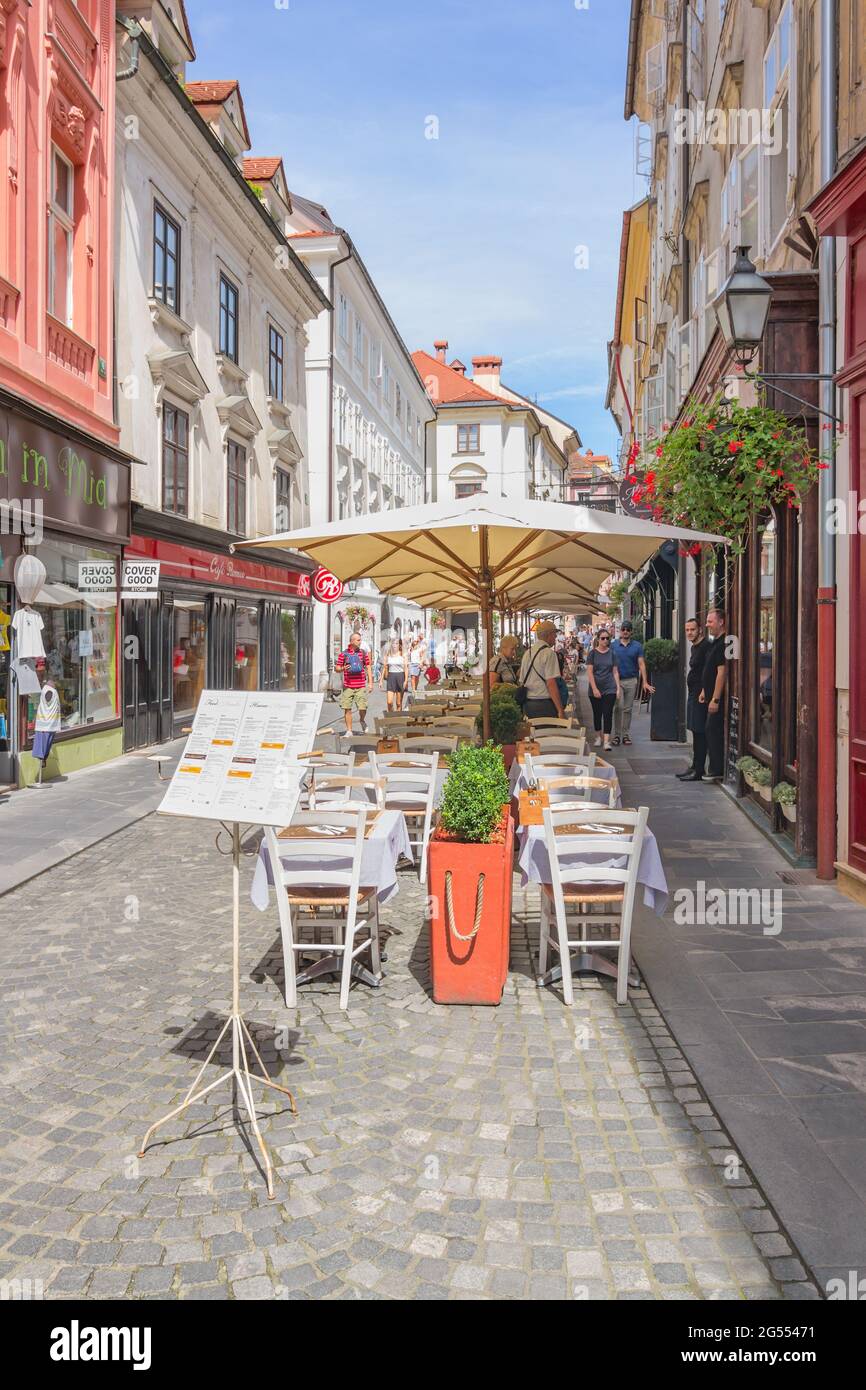 Ljubljana, Slovenia - August 15, 2018: Tourists and restaurant tables with sunshades share the picturesque Stari street in the old town Stock Photo