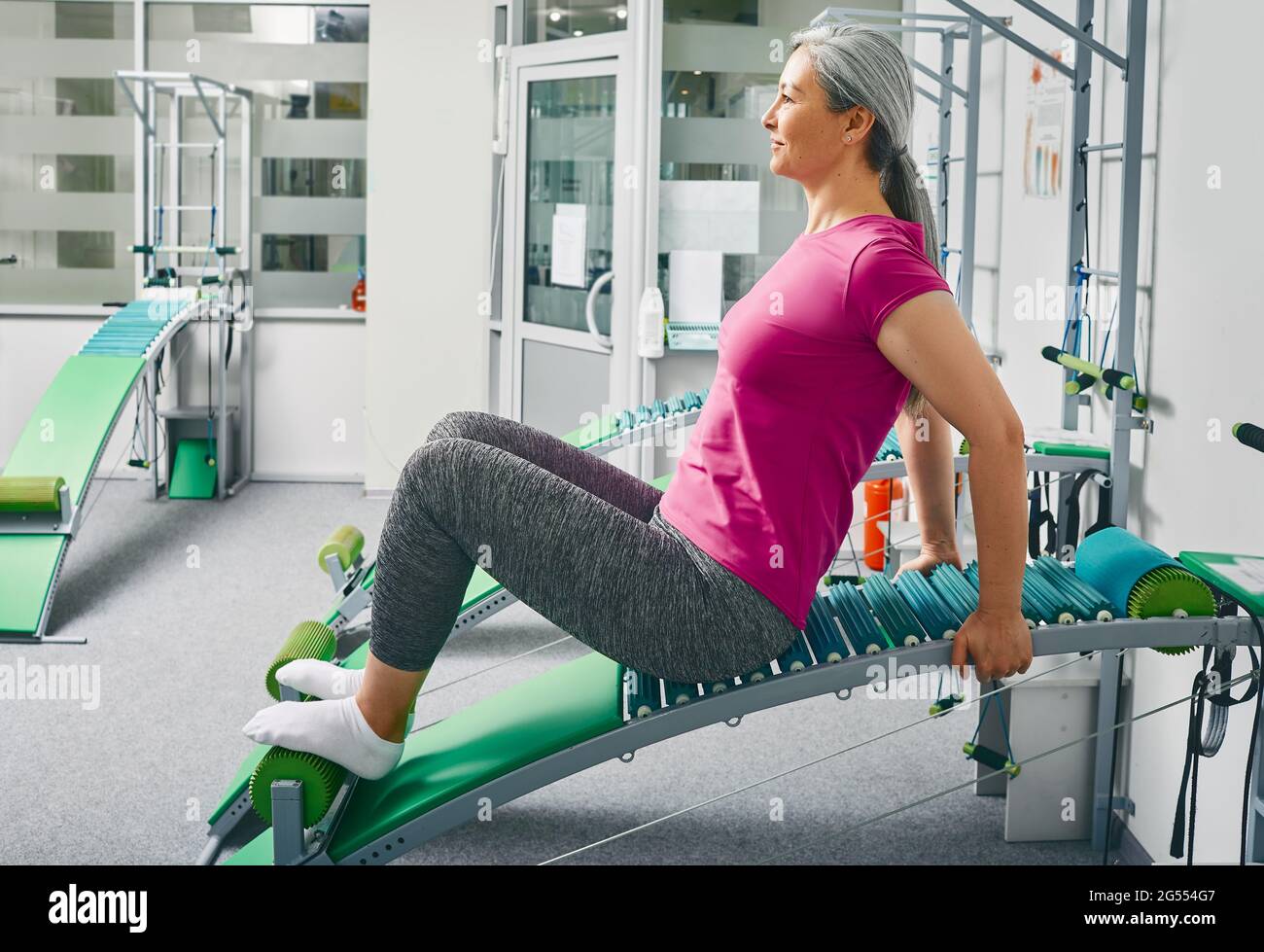 Mature woman doing recovery exercises on special vertebral equipment to restore the lumbar spine Stock Photo