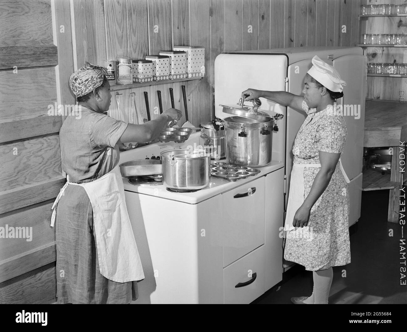 Two Female Workers preparing Hot Lunch for Agricultural Workers' Children in Kitchen of Day Nursery, Okeechobee Migratory Labor Camp, Belle Glade, Florida, USA, Marion Post Wolcott, U.S. Farm Security Administration, February 1941 Stock Photo