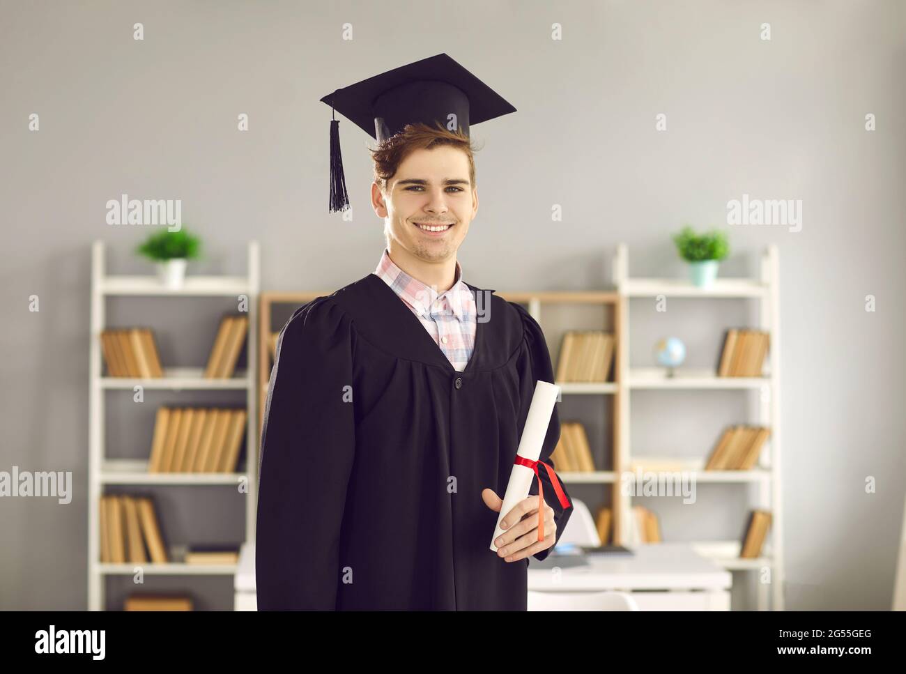 Graduation portrait of happy university student holding diploma and smiling at camera Stock Photo