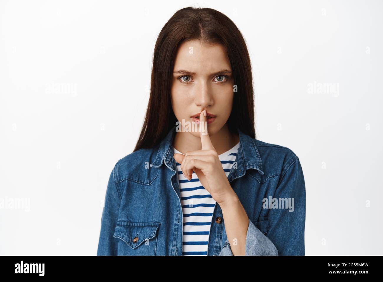 Close up of serious and angry woman hushing, press finger to lips in