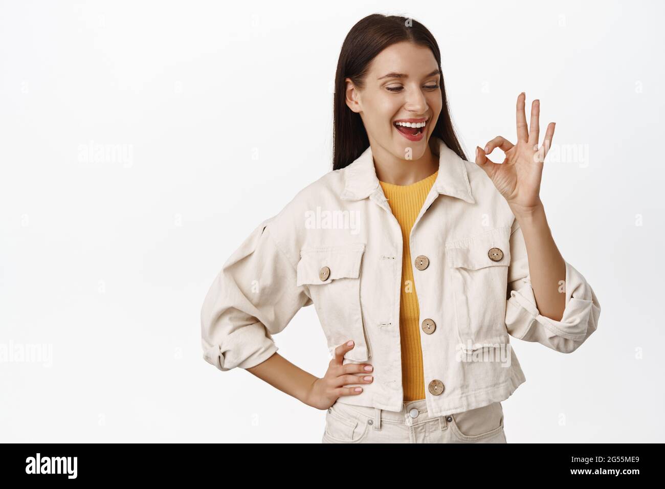 Zero problems. Smiling happy woman showing okay, OK sign and laughing, easygoing girl recommend smth, like and approve, praise excellent choice, white Stock Photo