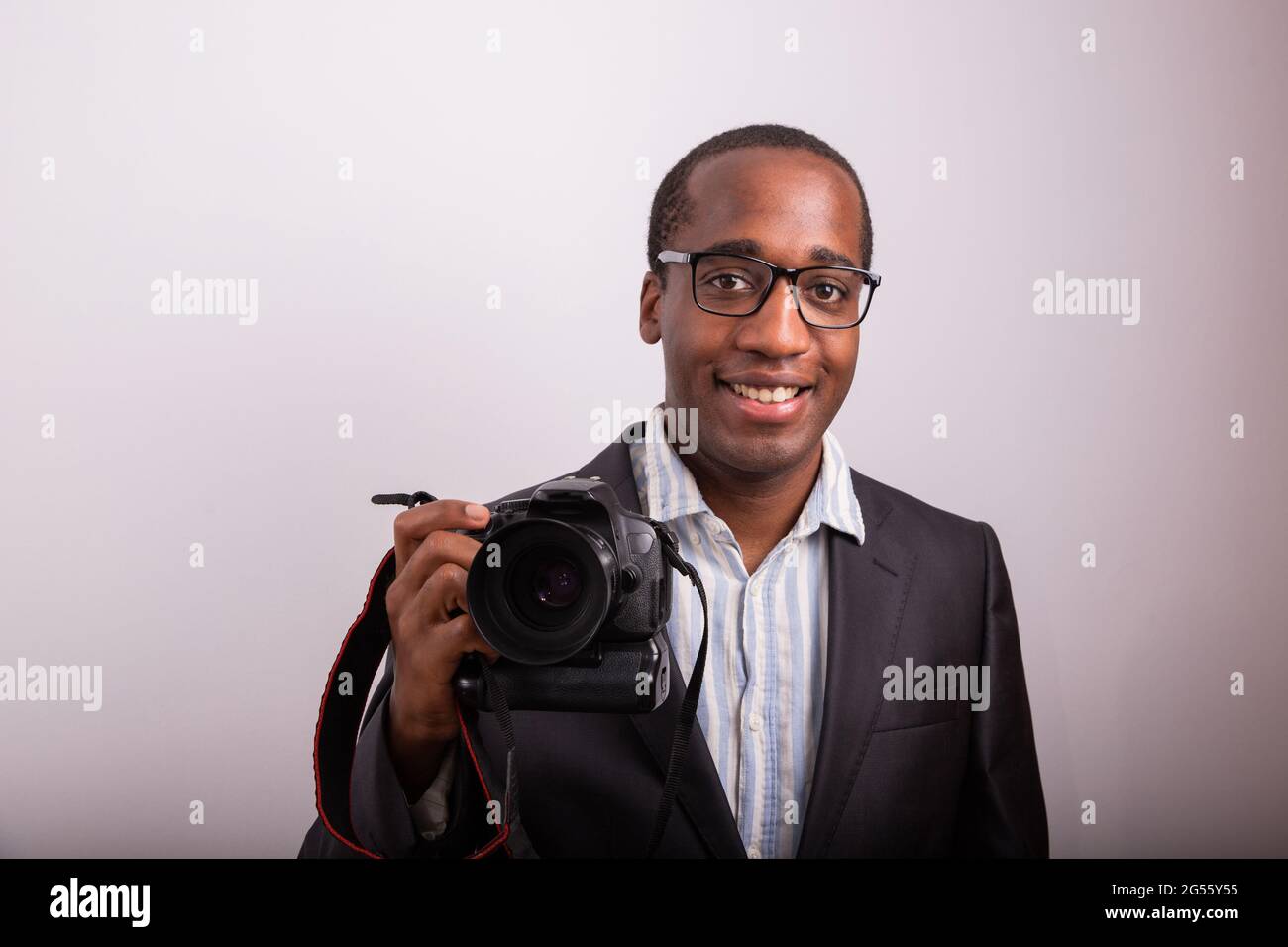 Smiling African photographer elegantly dressed with camera in hand. Model isolated on white background. Stock Photo