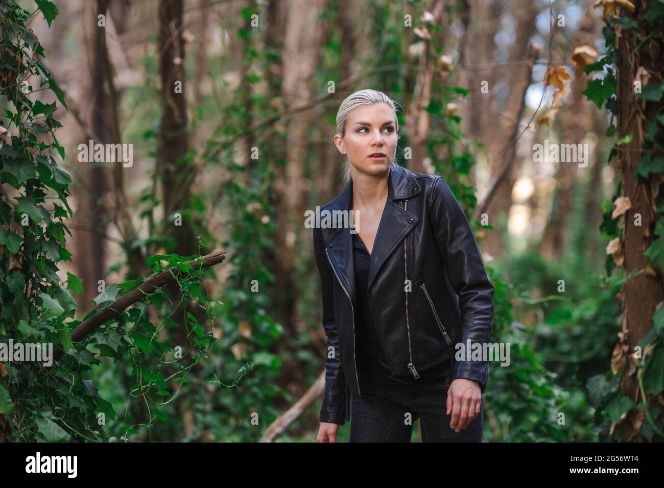 Fashion in unusual places, Young Woman in Edgy Motorcycle Jacket in the Forest Stock Photo