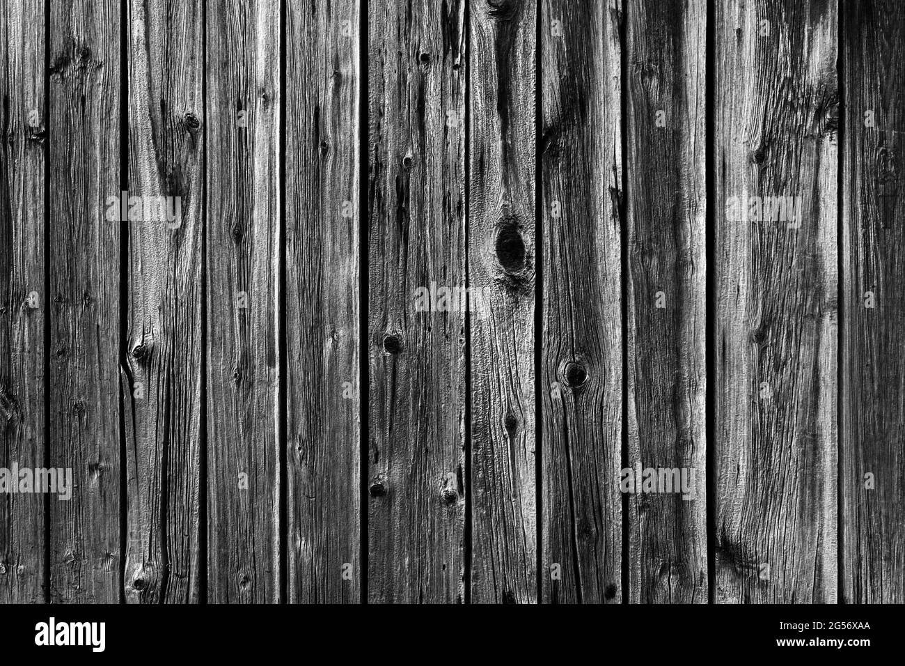 Black and white background photo of an old worn wooden fence made of planks. Stock Photo
