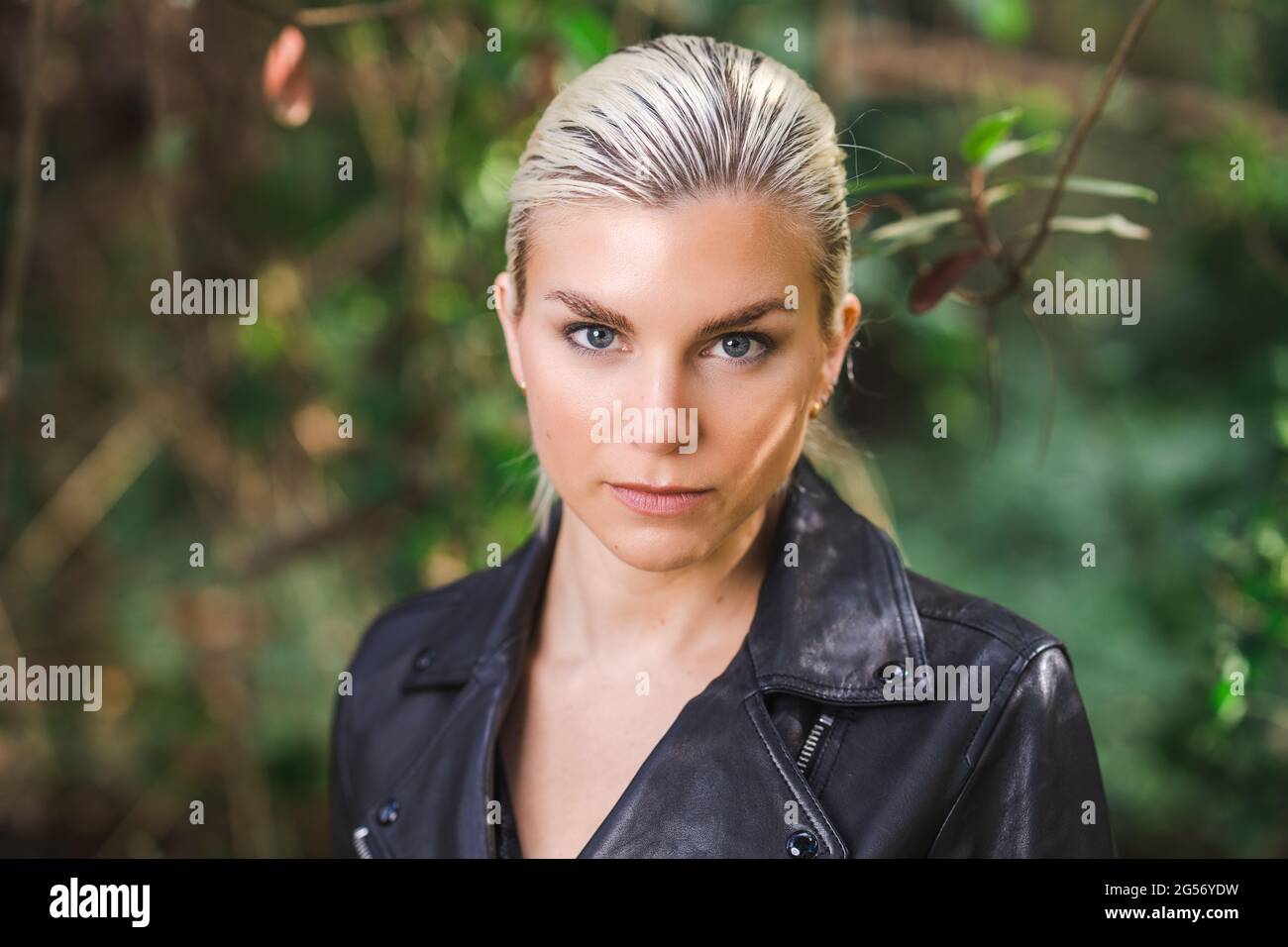 Fashion in unusual places, Young Woman in Edgy Motorcycle Jacket in the Forest Stock Photo