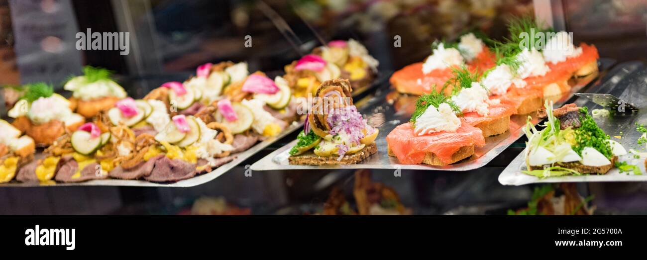Danish smorrebrod traditional open sandwich at Copenhagen food market store. Selection of fish sandwiches on display with seafood and meat, smoked Stock Photo