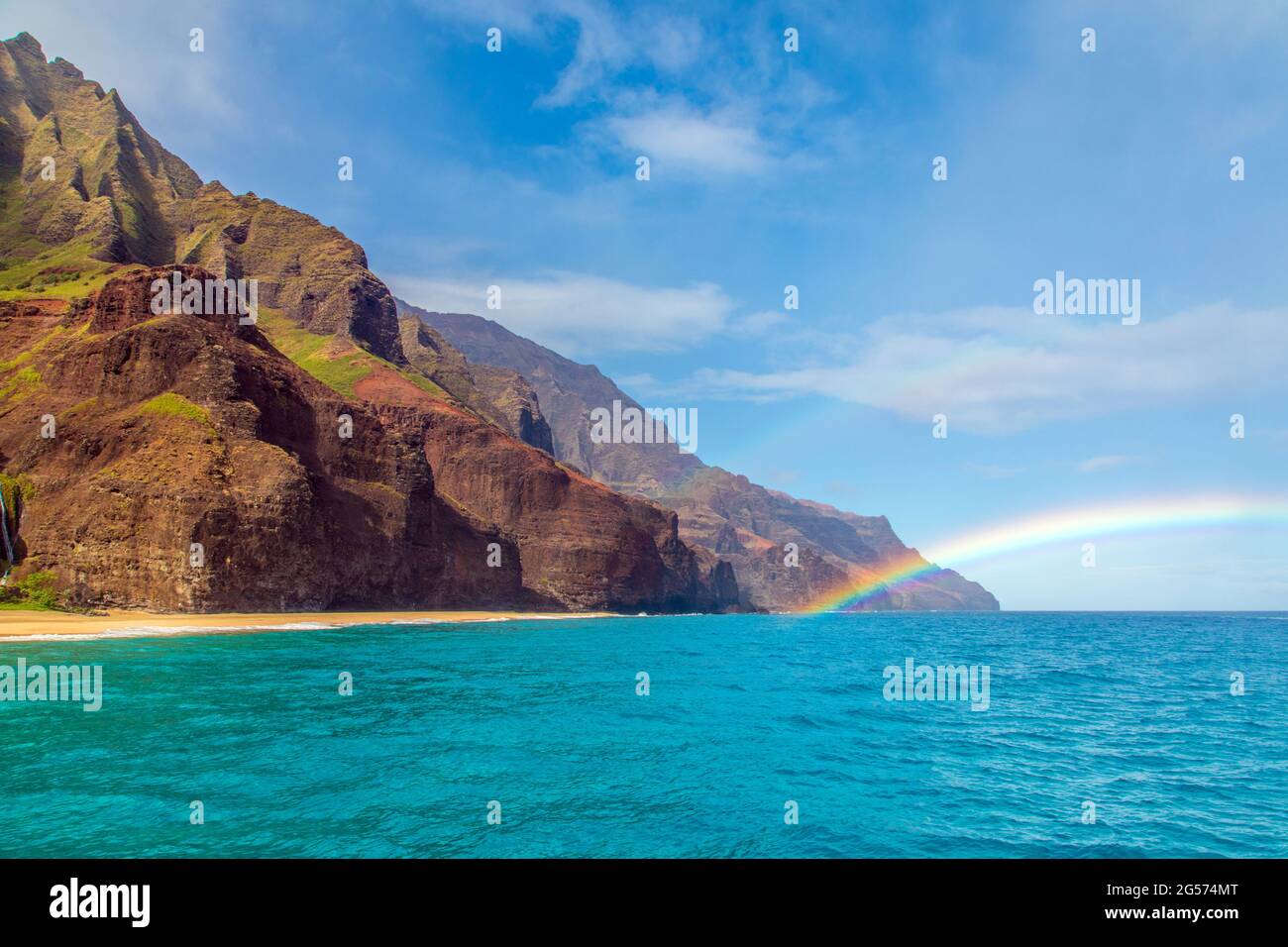 View of a rainbow off of Kauai's rugged Nā Pali Coast, where Kauai's rugged, remote coastline meets the Pacific Ocean Stock Photo