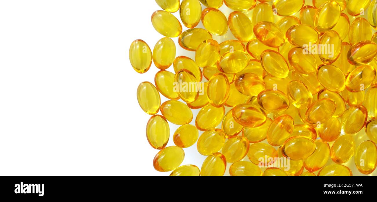 Yellow vitamin E capsules on a white background with copy space, top