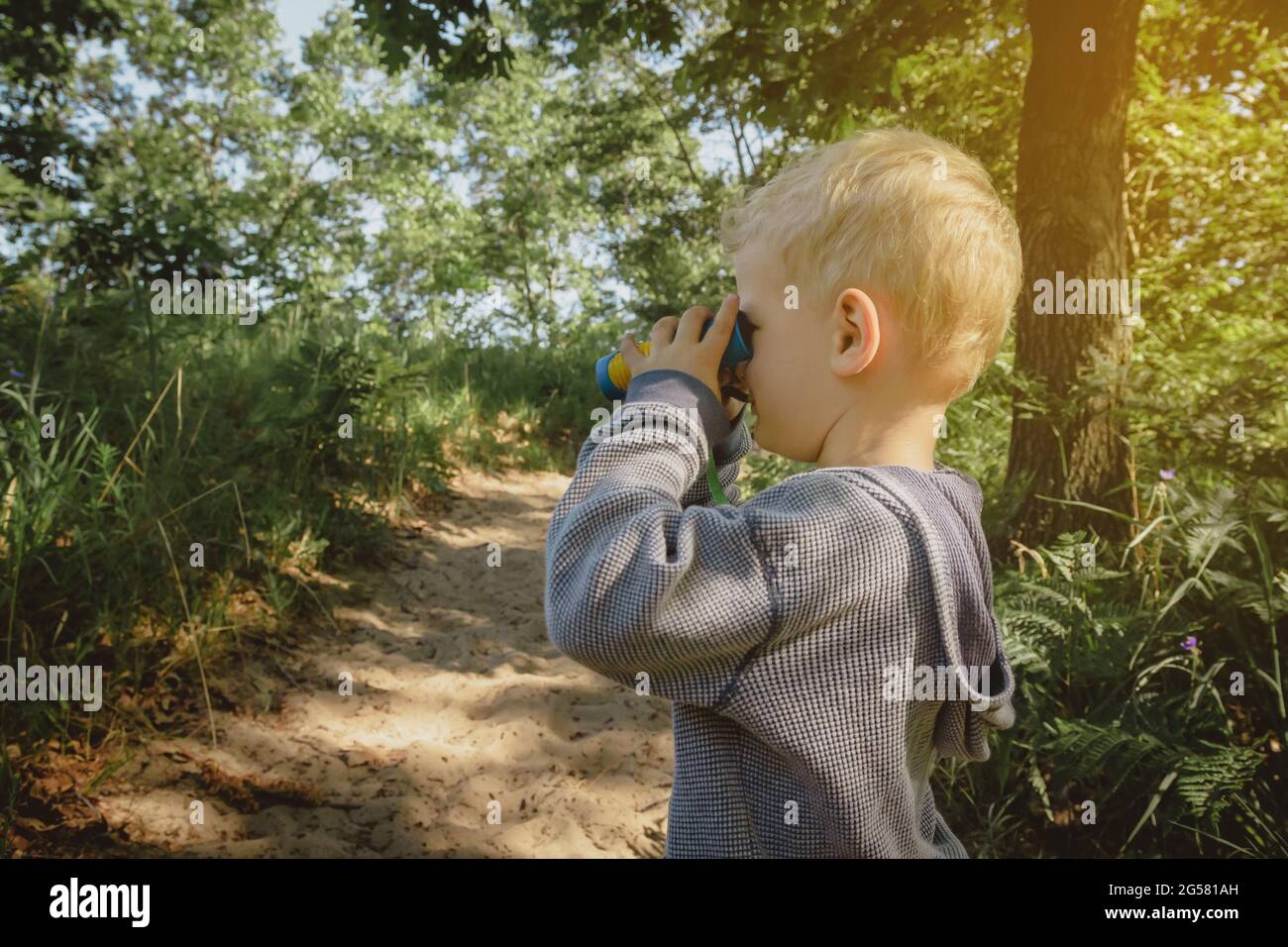 Young boy hiking and bird watching on a trail with binoculars at Indiana Dunes State Park. Stock Photo