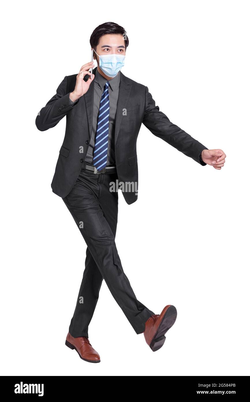 young businessman talking on  mobile phone, walking and wearing a protective medical mask isolated on white background Stock Photo