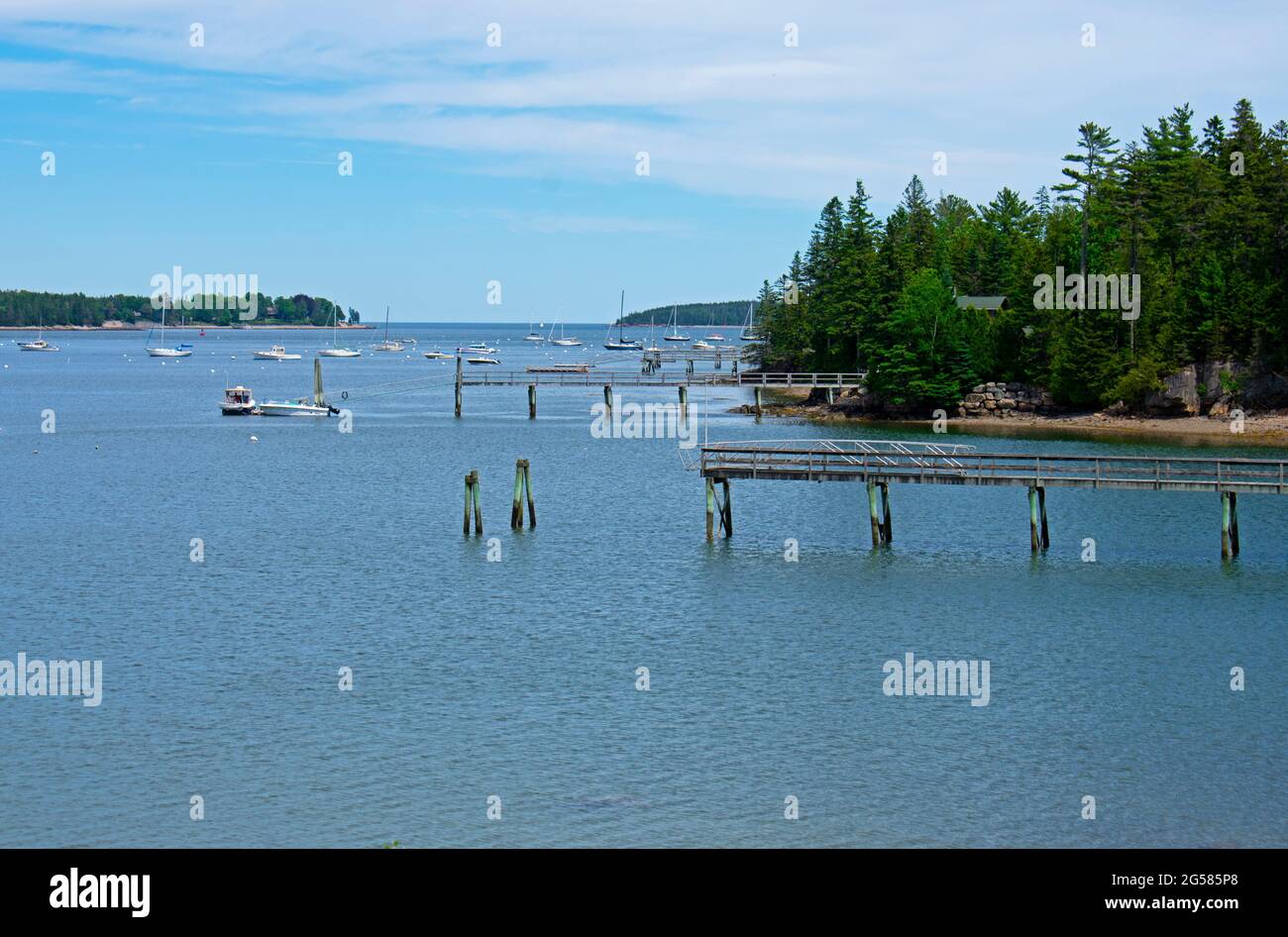 Variety of nautical vessels moored on calm blue waters of a Maine harbor under a blue sky with some cirrus clouds -04 Stock Photo