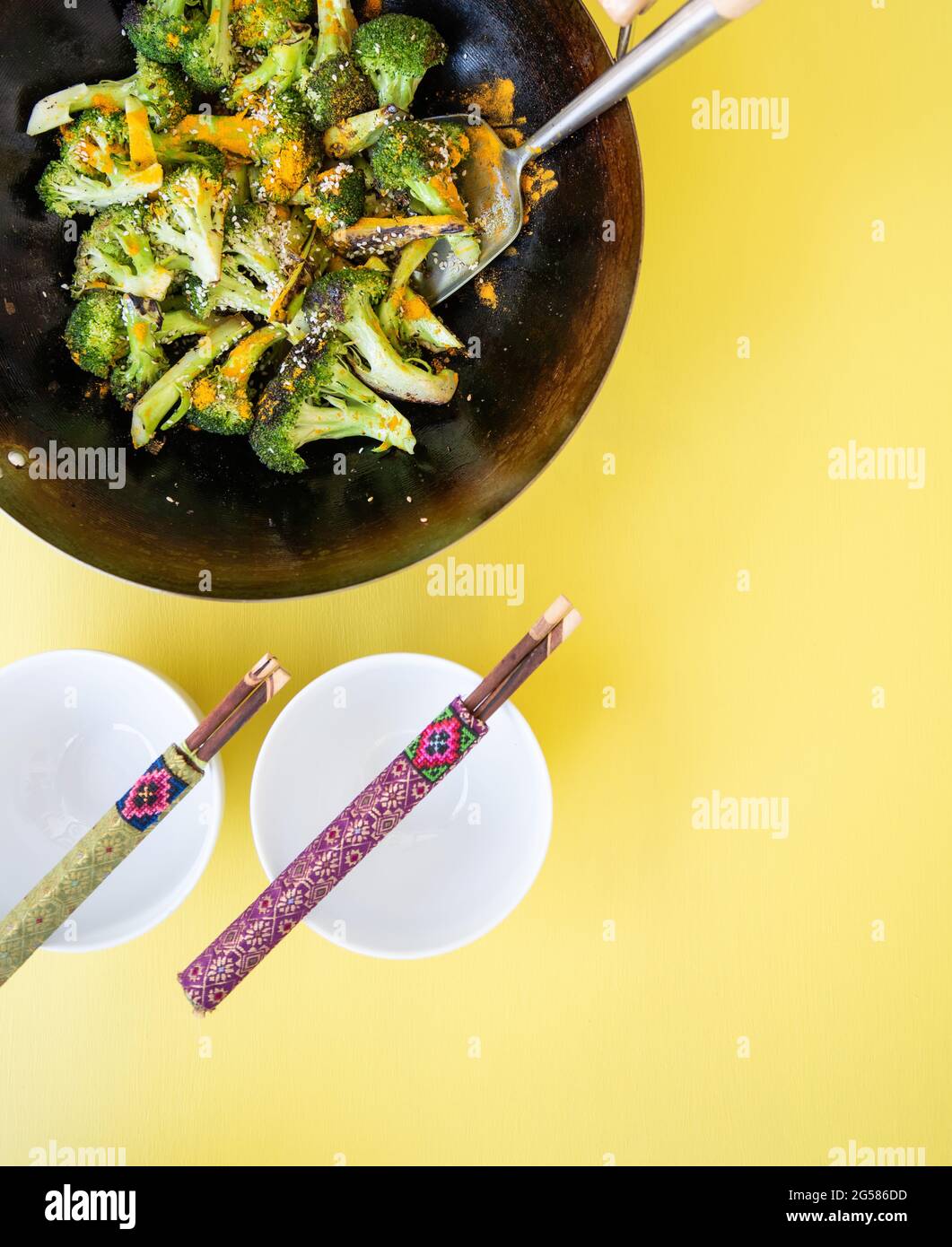 Flat lay of Asian wok dish with two sets of chopsticks on bowls. Stock Photo